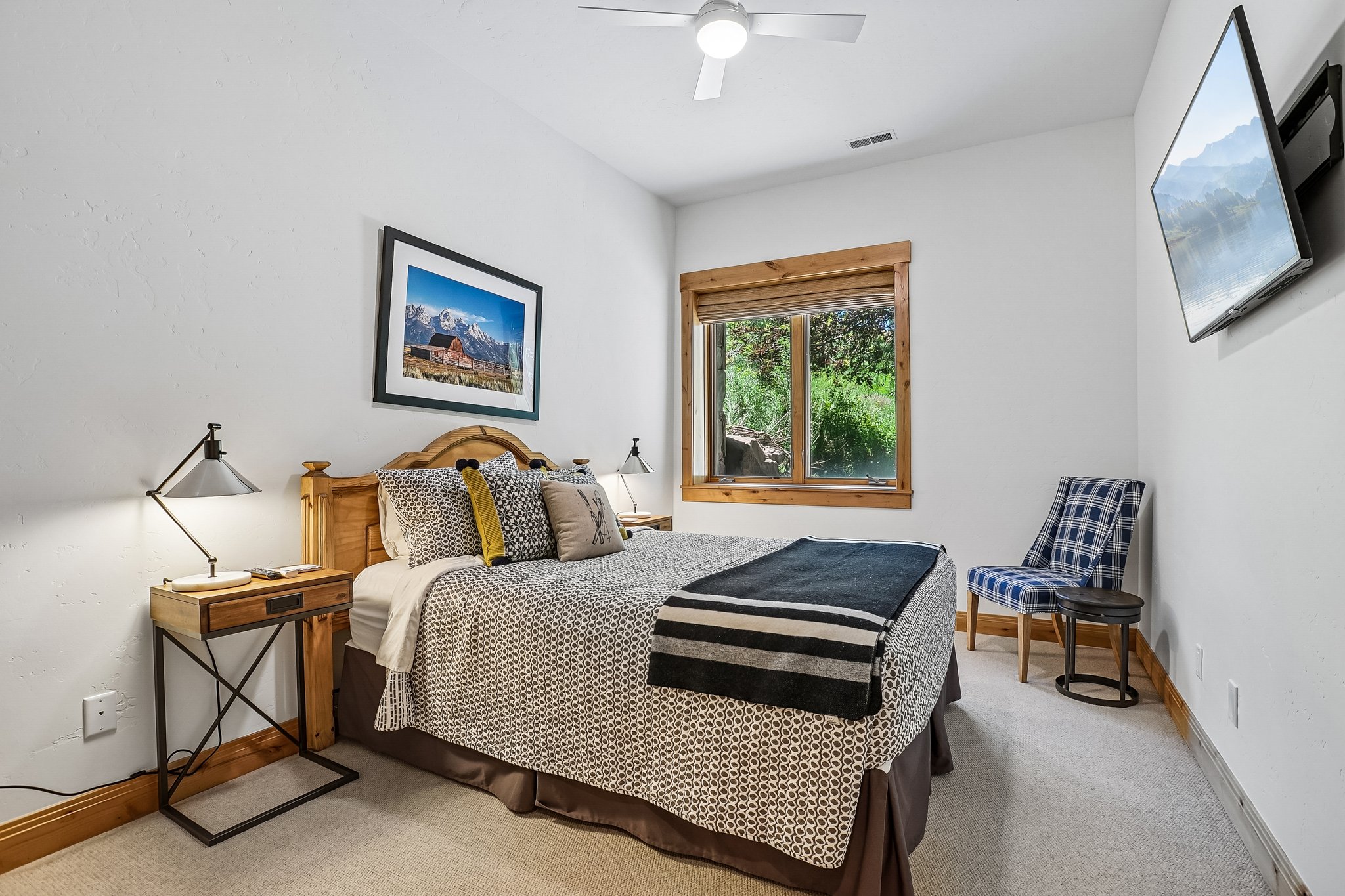 Carpeted room with a ceiling fan, a window with wood trim, and a wall-mounted television