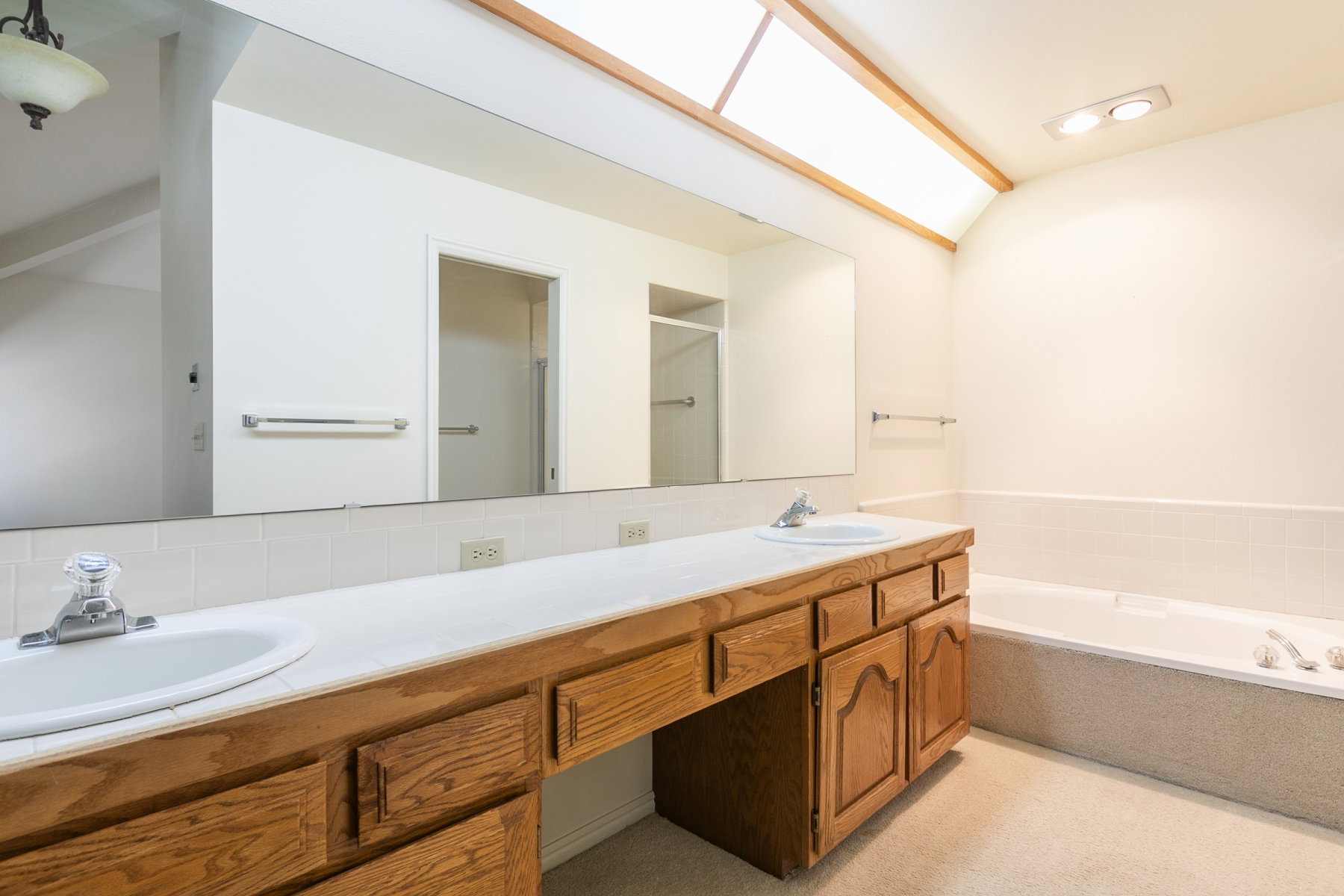 Dual vanity with wood-finish cabinetry, integrated sinks, and an expansive mirror