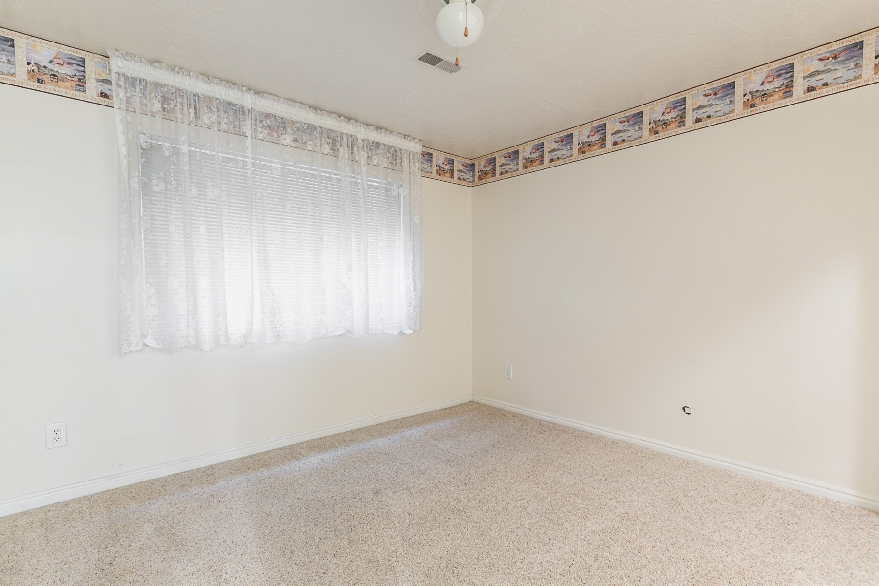 Carpeted room with a ceiling-mounted light fixture and a window featuring blinds