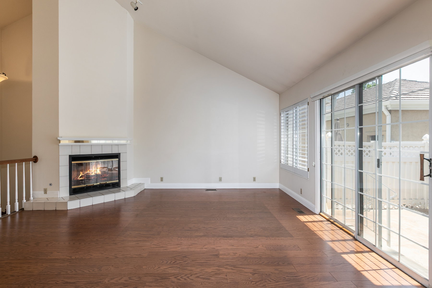 Living space featuring wood-finish flooring, a corner fireplace with a tile surround and hearth, and a vaulted ceiling