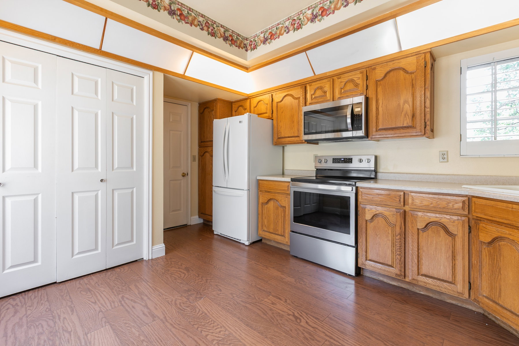 Kitchen featuring wood-finish flooring, wood cabinetry, stainless steel range, and stainless steel microwave