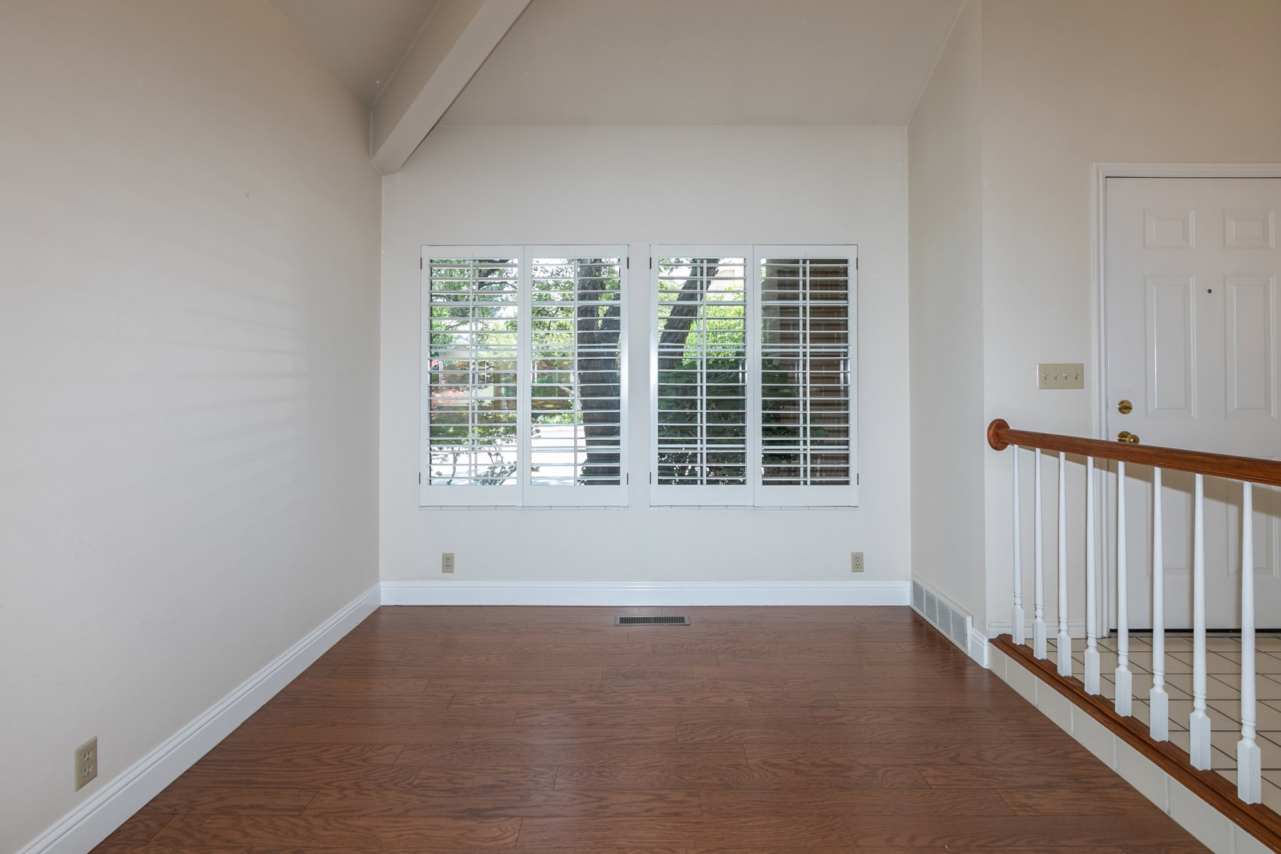 Interior space featuring wood-finish flooring, white baseboards, and a vaulted ceiling with exposed beam