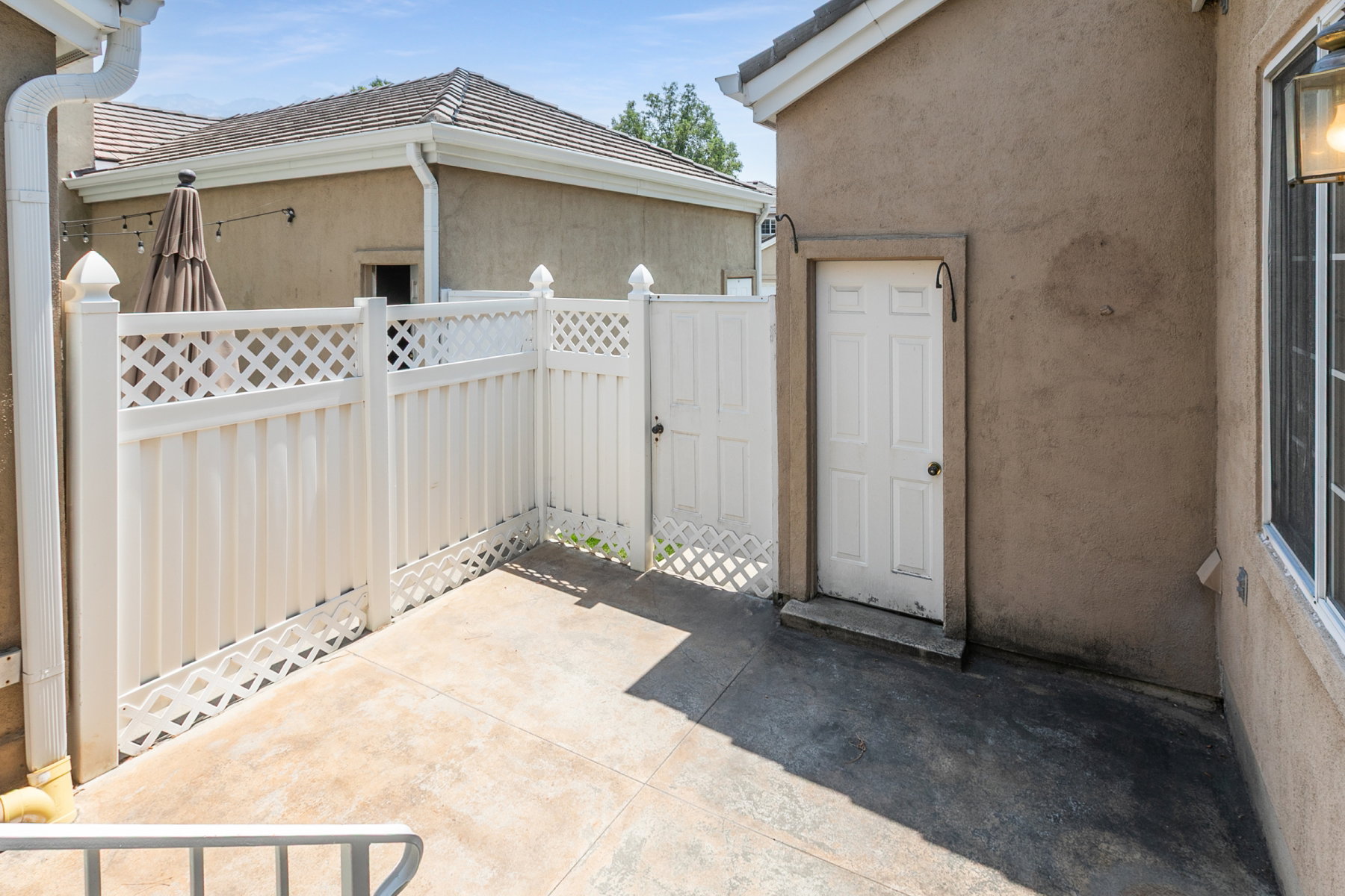 Private patio space featuring a white lattice-top fence and gate