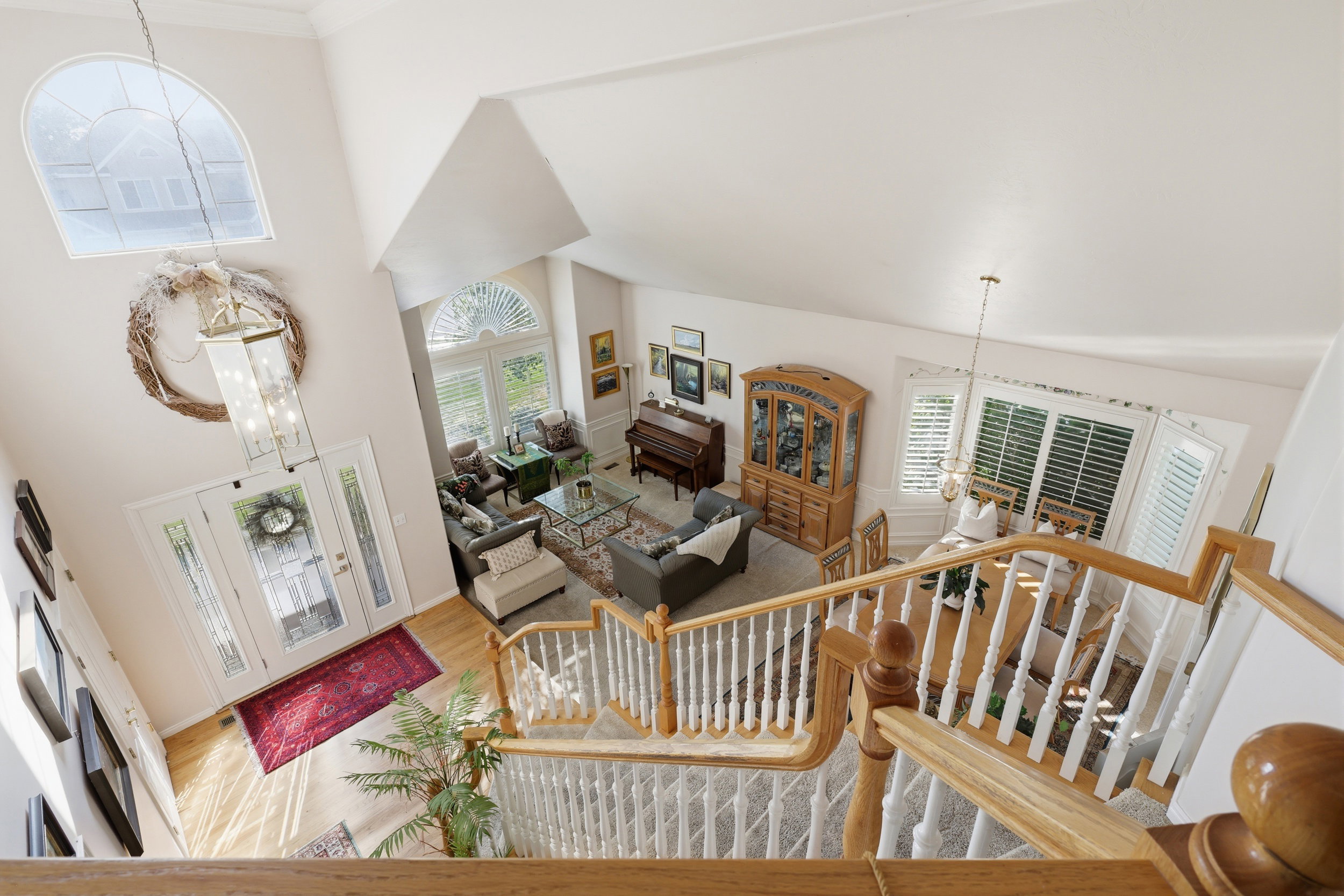 Two-story foyer featuring a grand staircase with white spindles and wood handrail, hardwood flooring, and a decorative chandelier