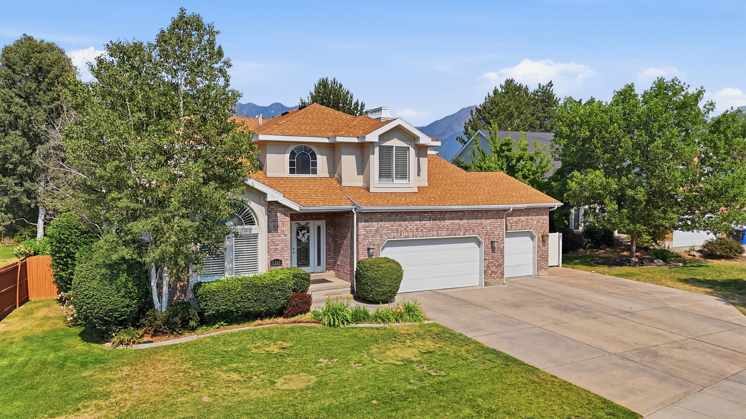 Traditional two-story residence featuring a brick facade with stucco accents and a brown shingle roof