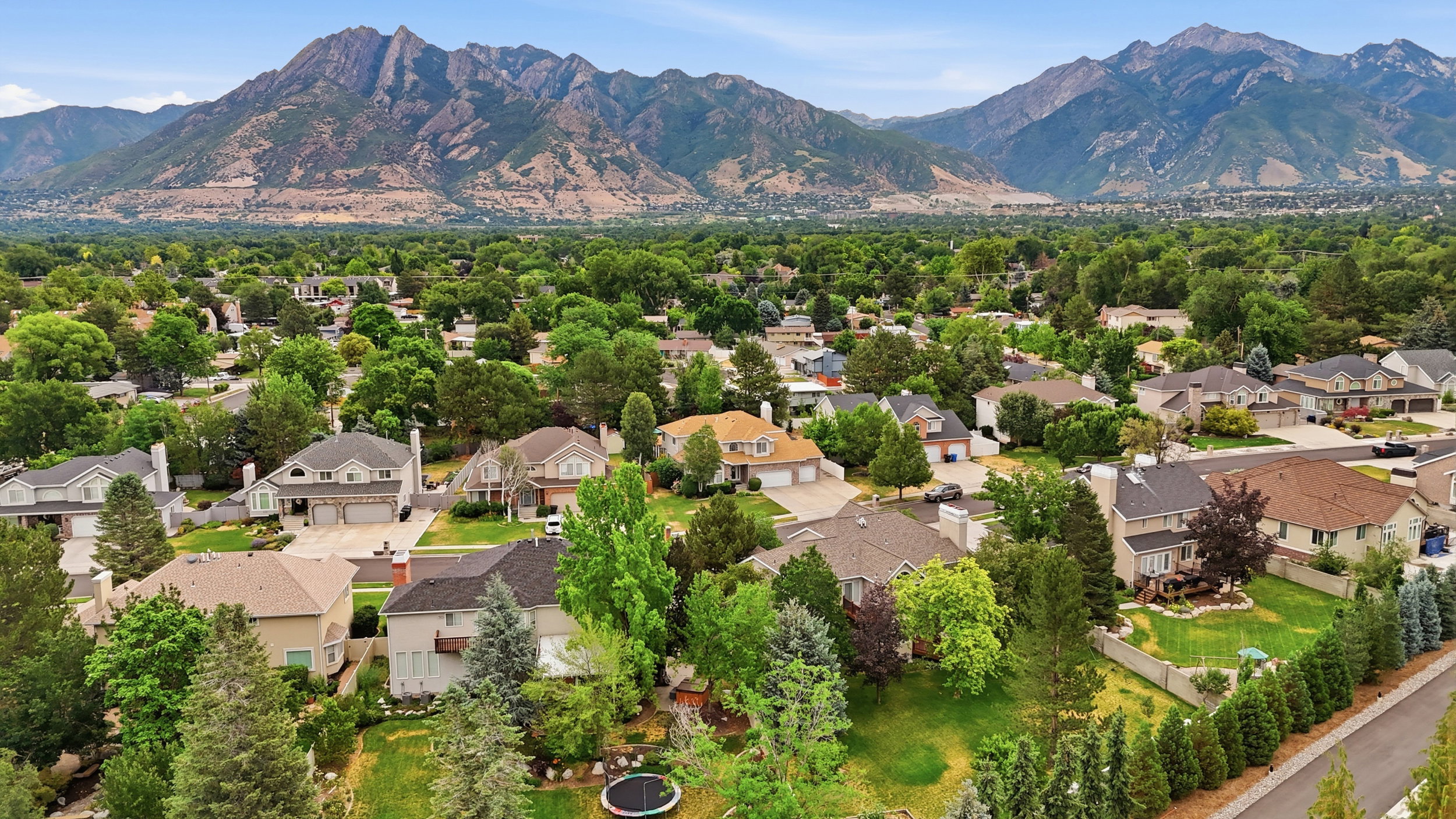 Expansive residential area featuring numerous properties amidst mature trees and mountainous backdrops