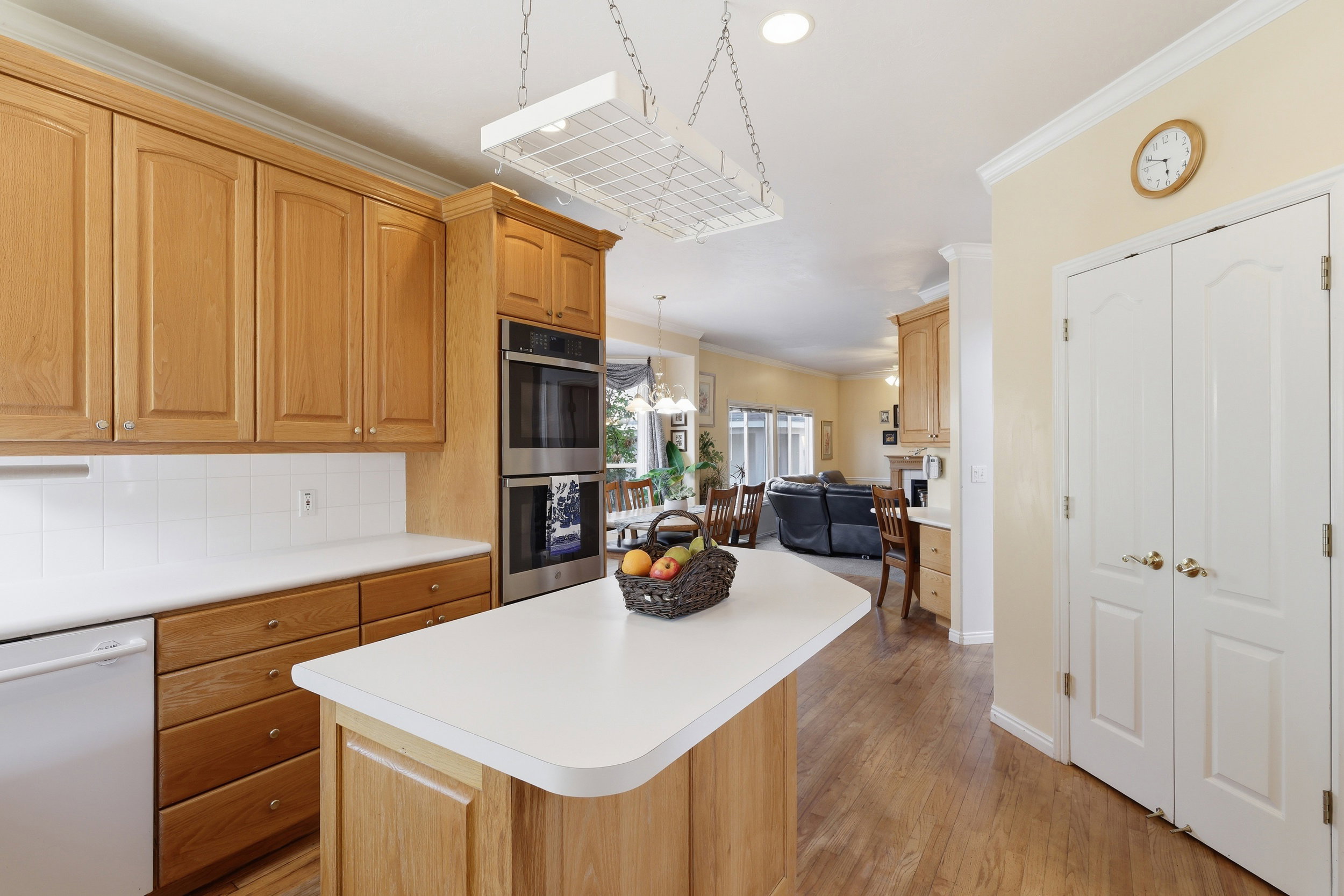 Kitchen featuring wood-finish cabinetry, white countertops, built-in double ovens, and wood-finish flooring