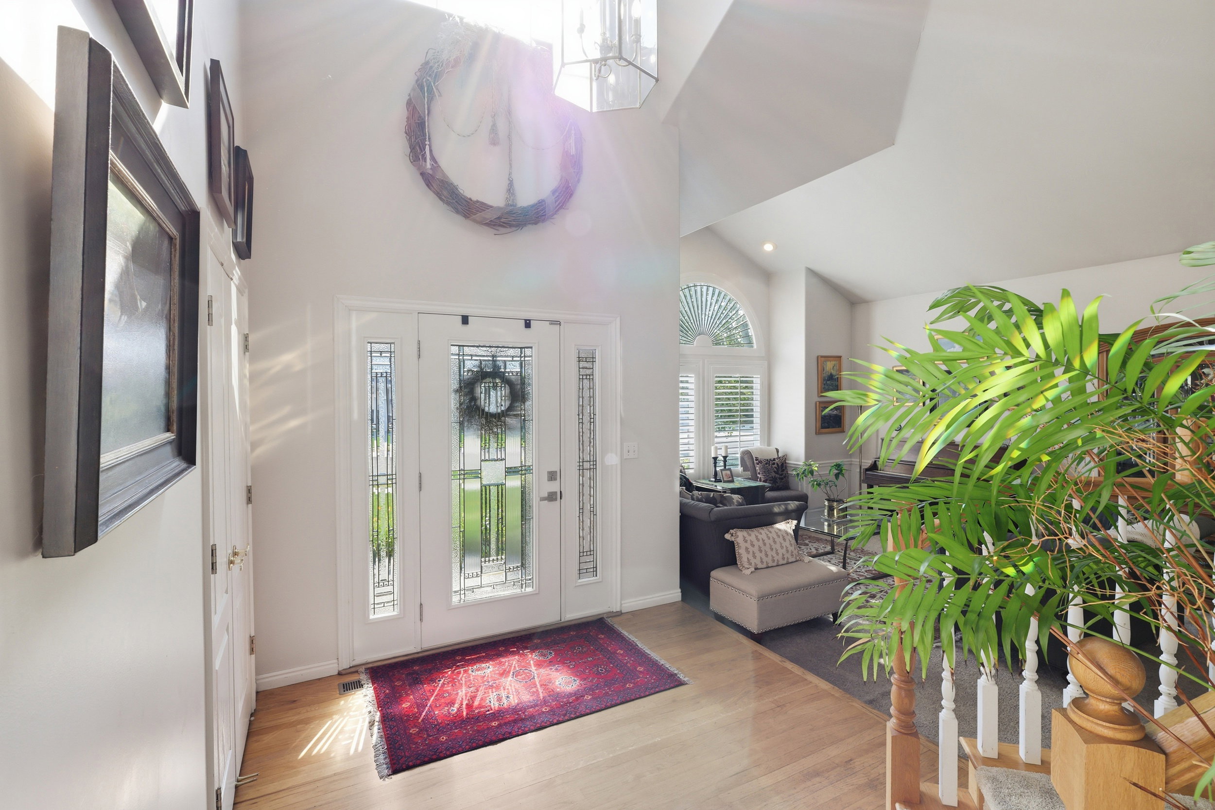 Foyer featuring a double entry door with decorative glass inserts, transom window, vaulted ceiling, and wood-finish flooring