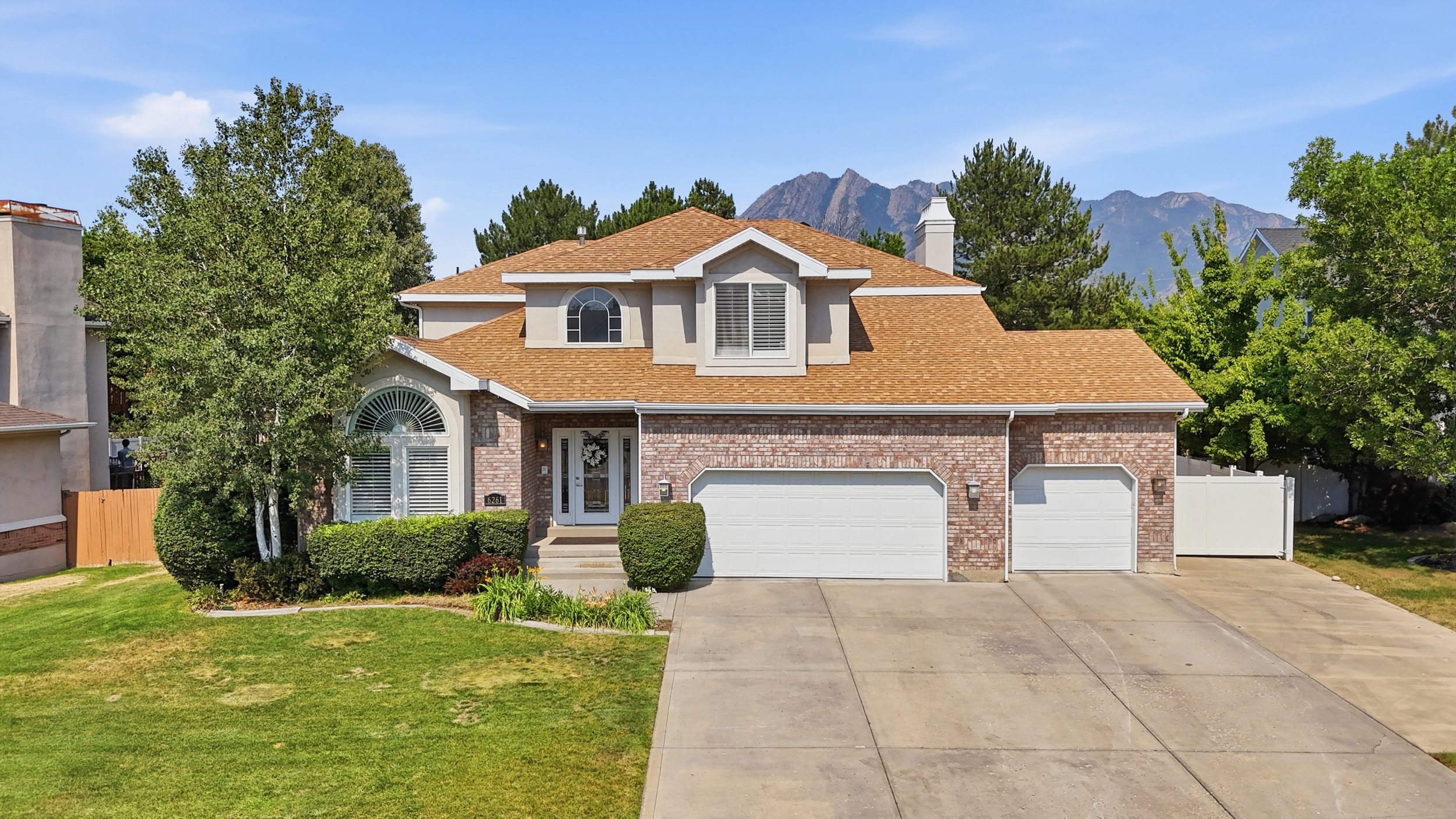 Traditional-style home featuring a brick facade, a multi-gabled roof, and an arched entry window