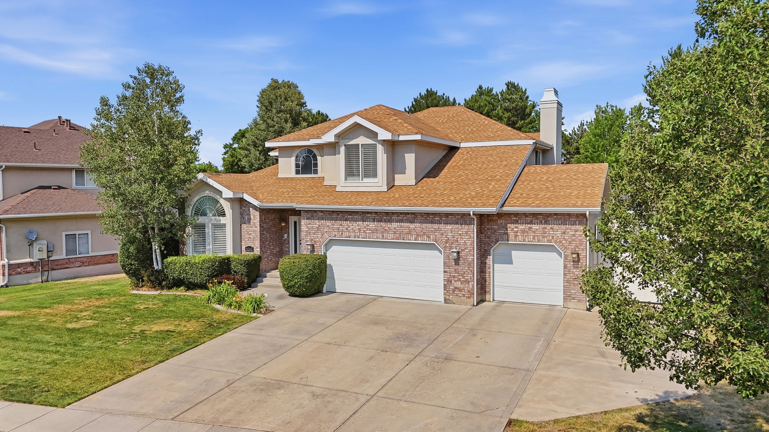 Brick facade home featuring a prominent arched window, a two-car garage, and an additional single-car garage