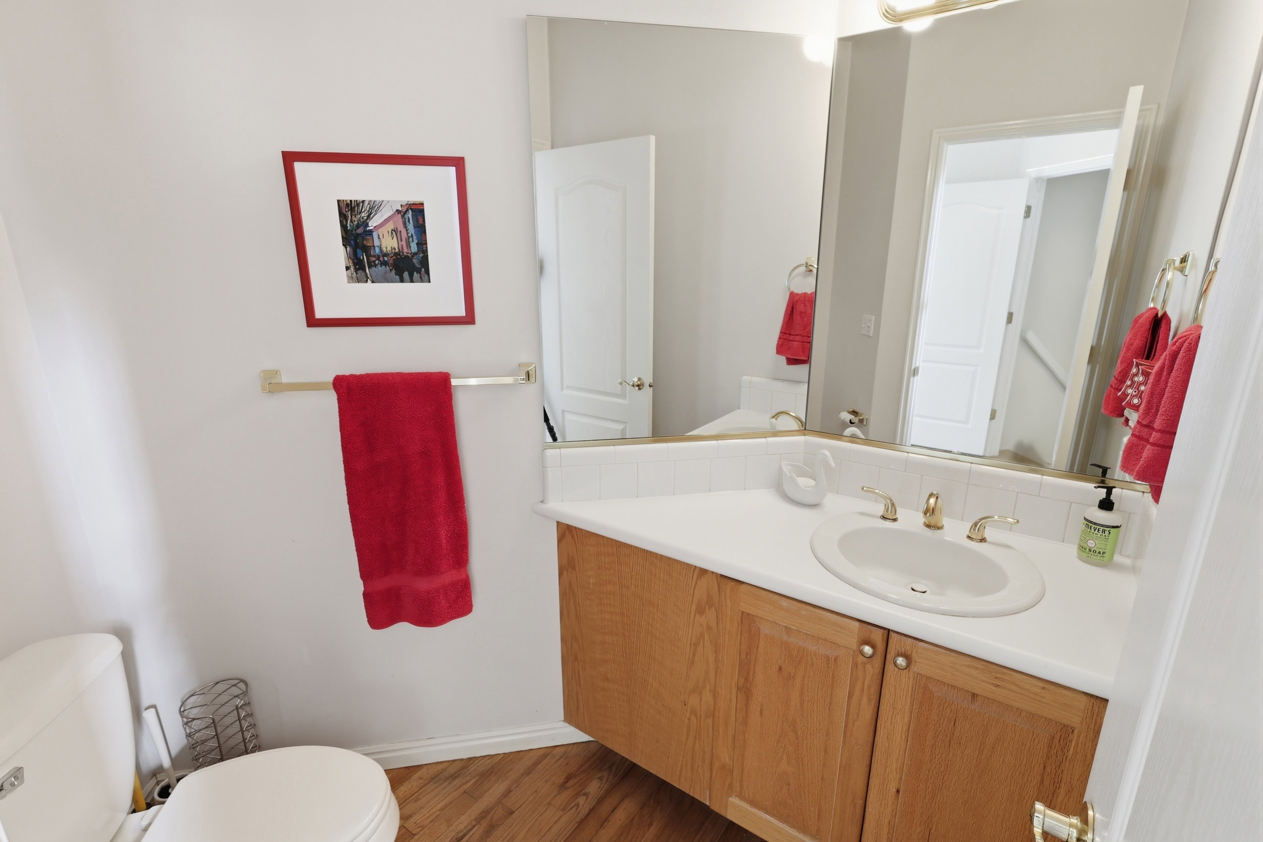 Bathroom featuring a wood-finish vanity with a white countertop, an integrated sink, and brass-finish fixtures