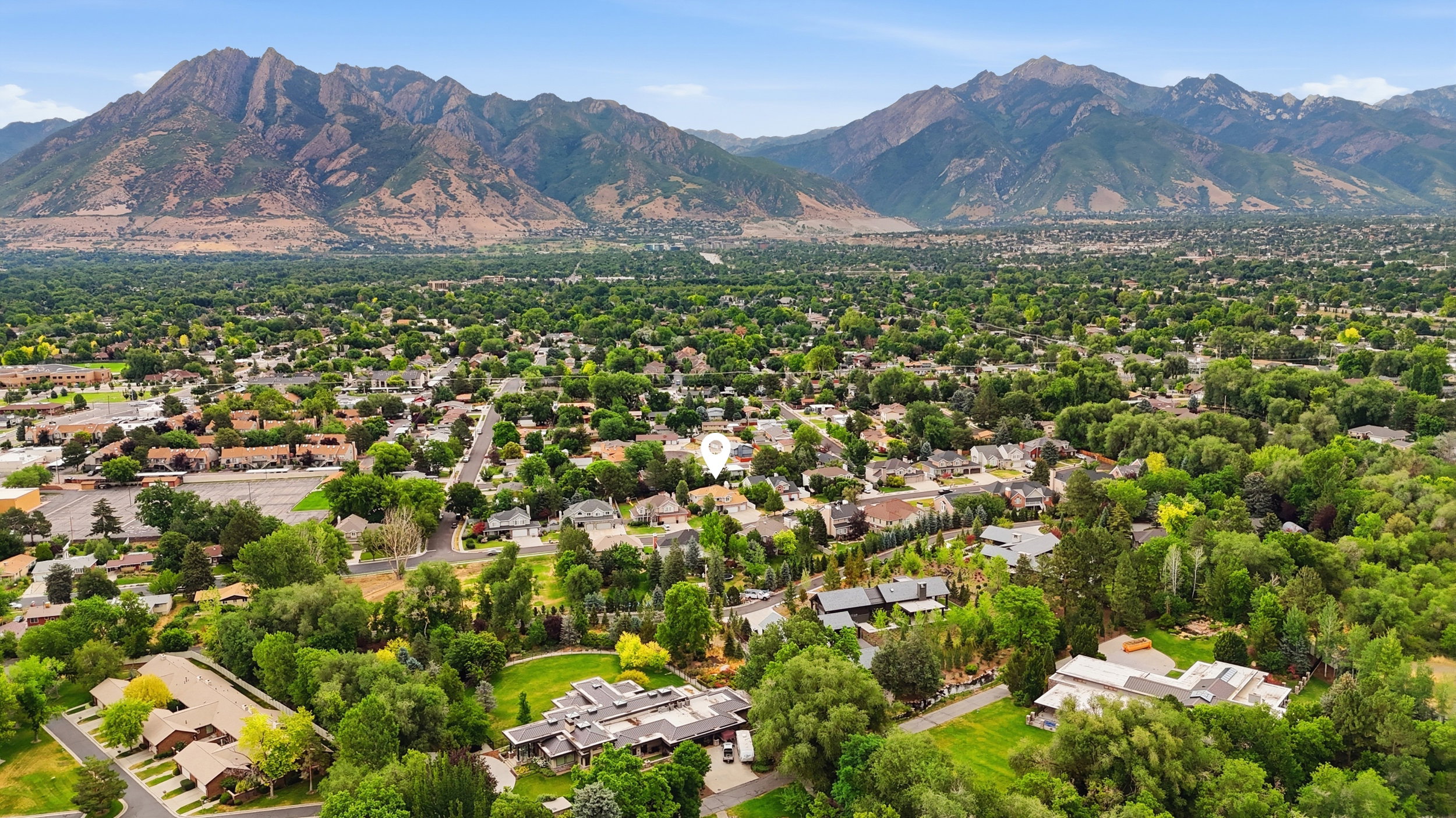 Expansive mountain range backdrop framing a residential area with mature tree canopy