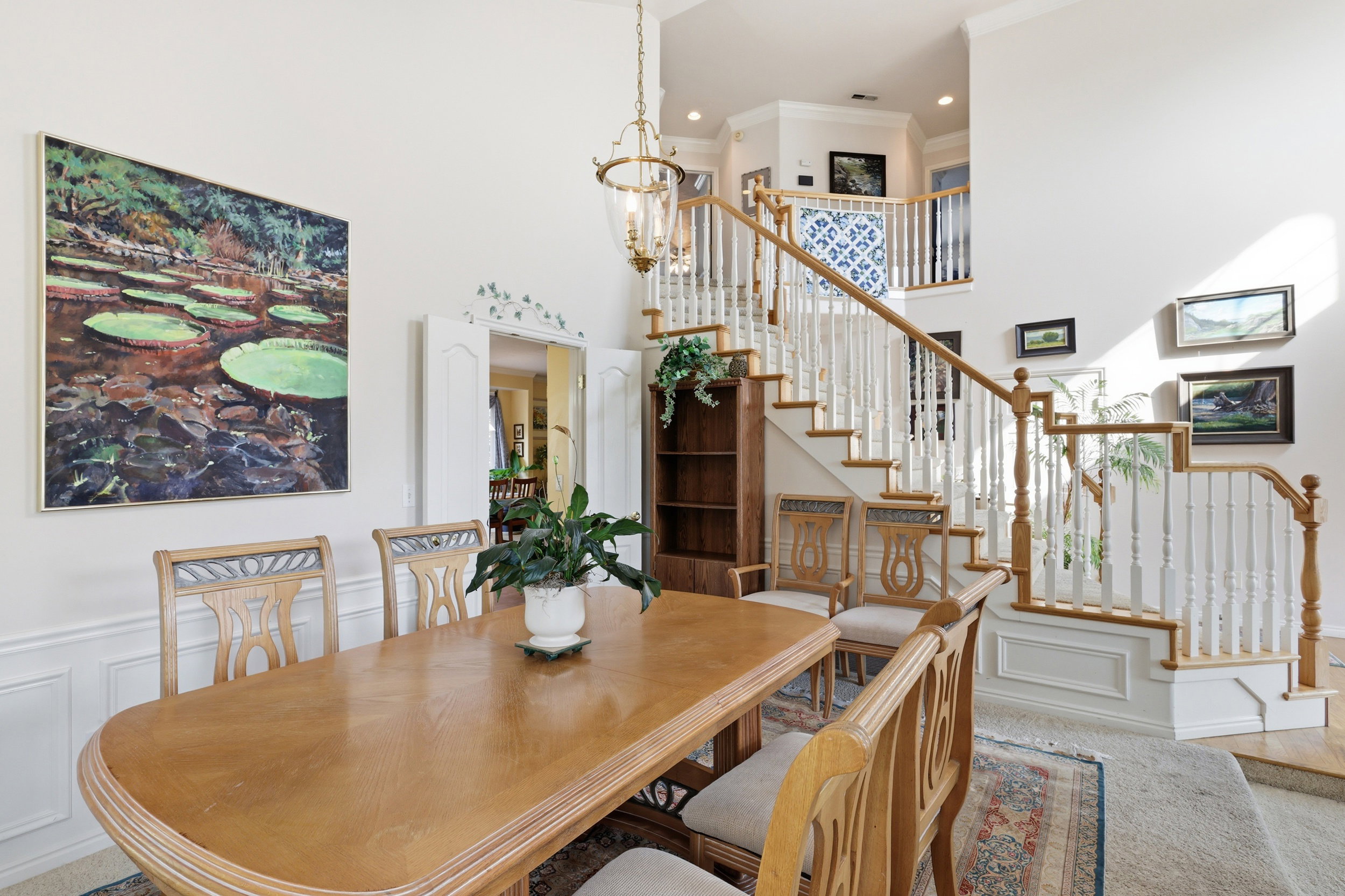 Two-story foyer with a grand staircase featuring white balusters and a wood handrail