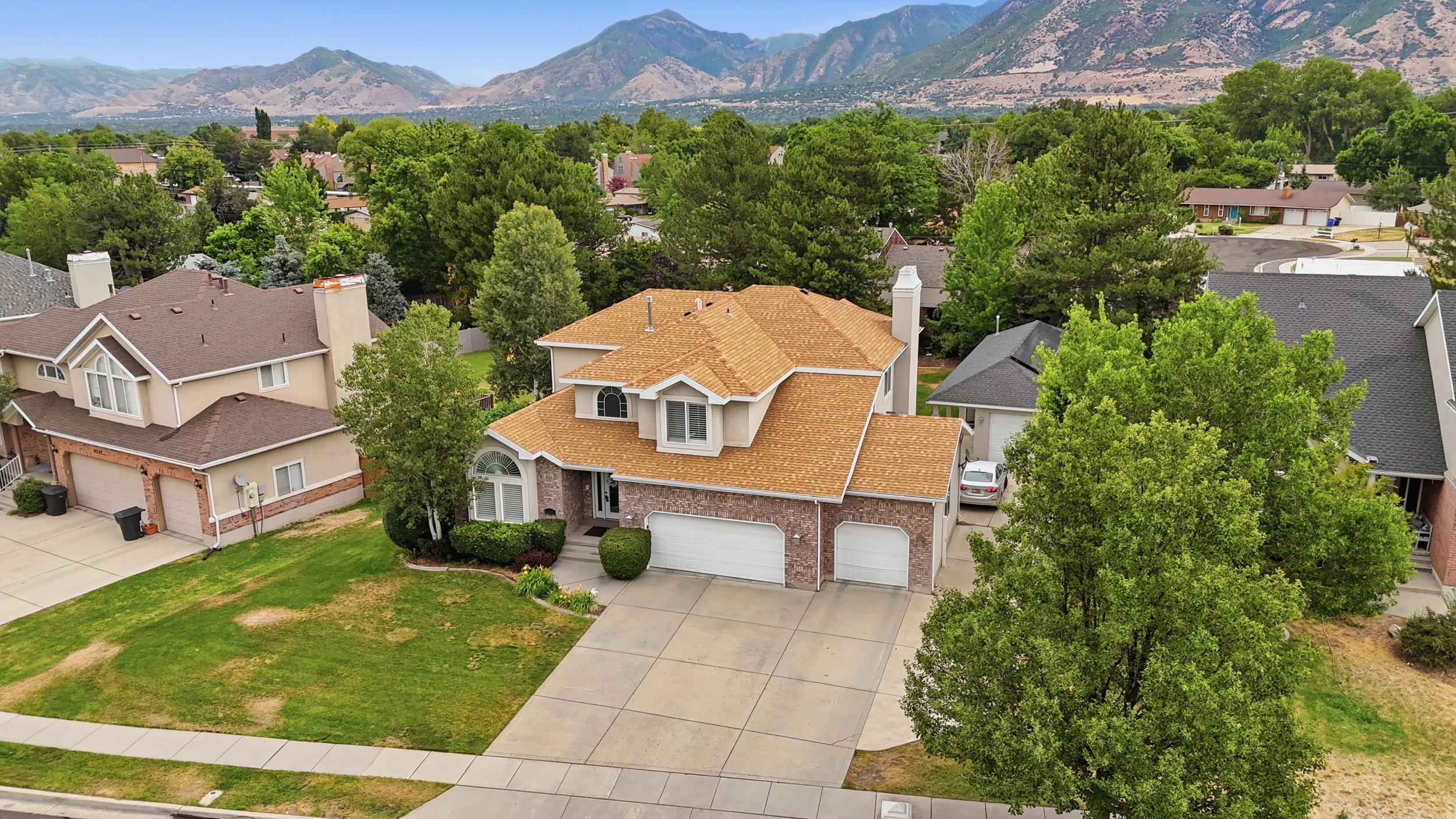 Two-story residence featuring a brick facade, multi-car garage, and a light-colored shingle roof