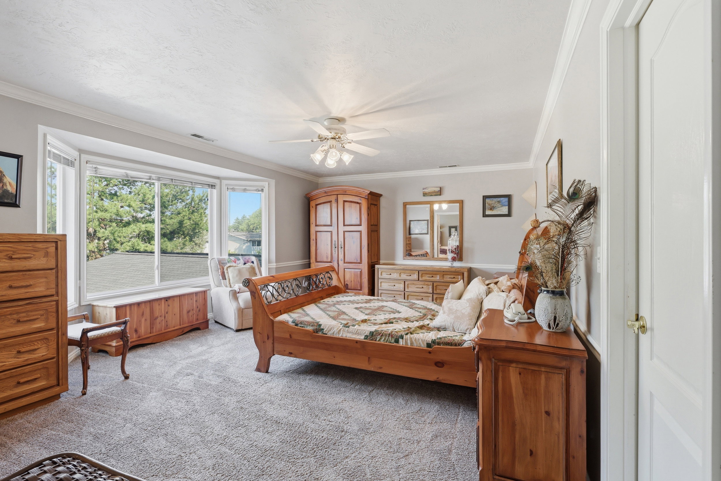 Carpeted room featuring a bay window, crown molding, and a ceiling fan