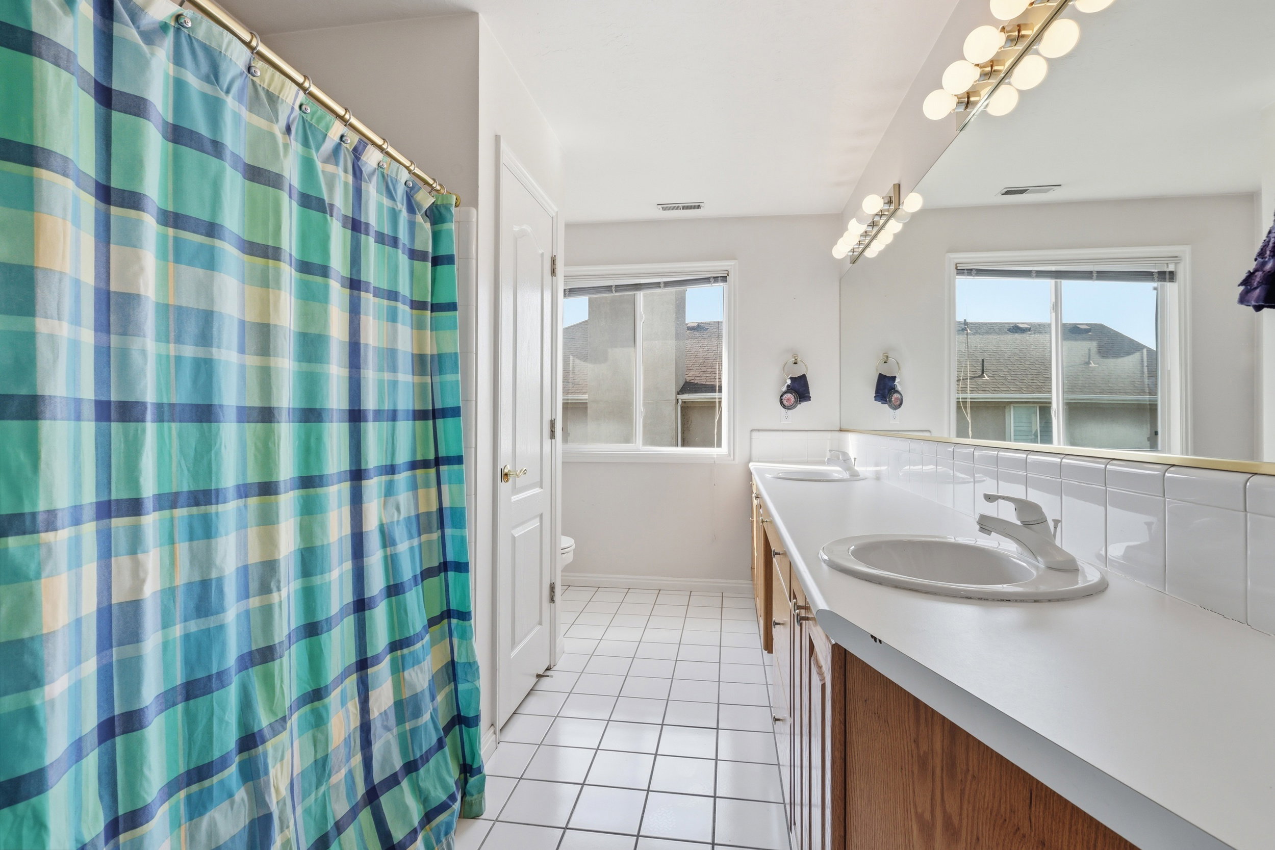 Bathroom featuring a dual vanity with white countertops, integrated sinks, and wood-finish cabinetry