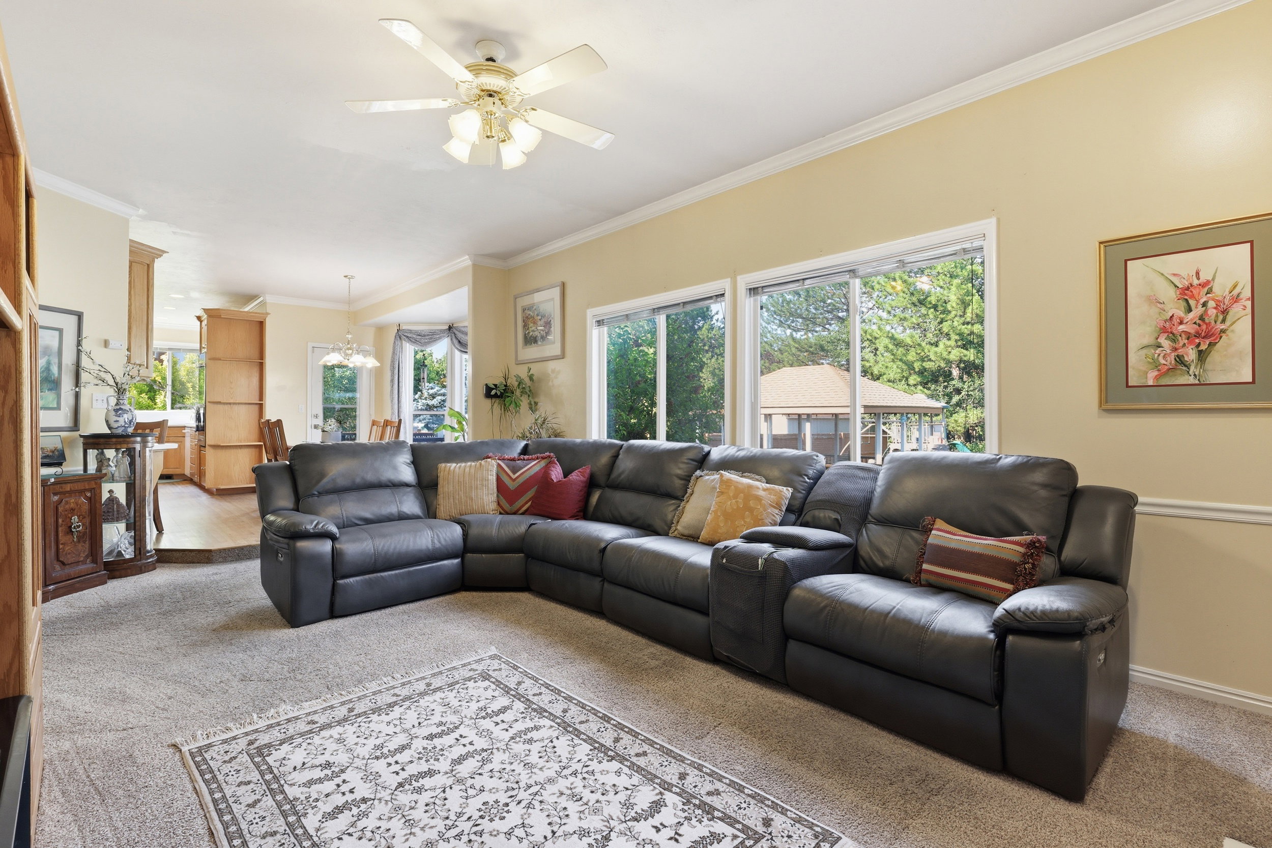 Living area featuring neutral wall tones, crown molding, and a ceiling fan with integrated lighting