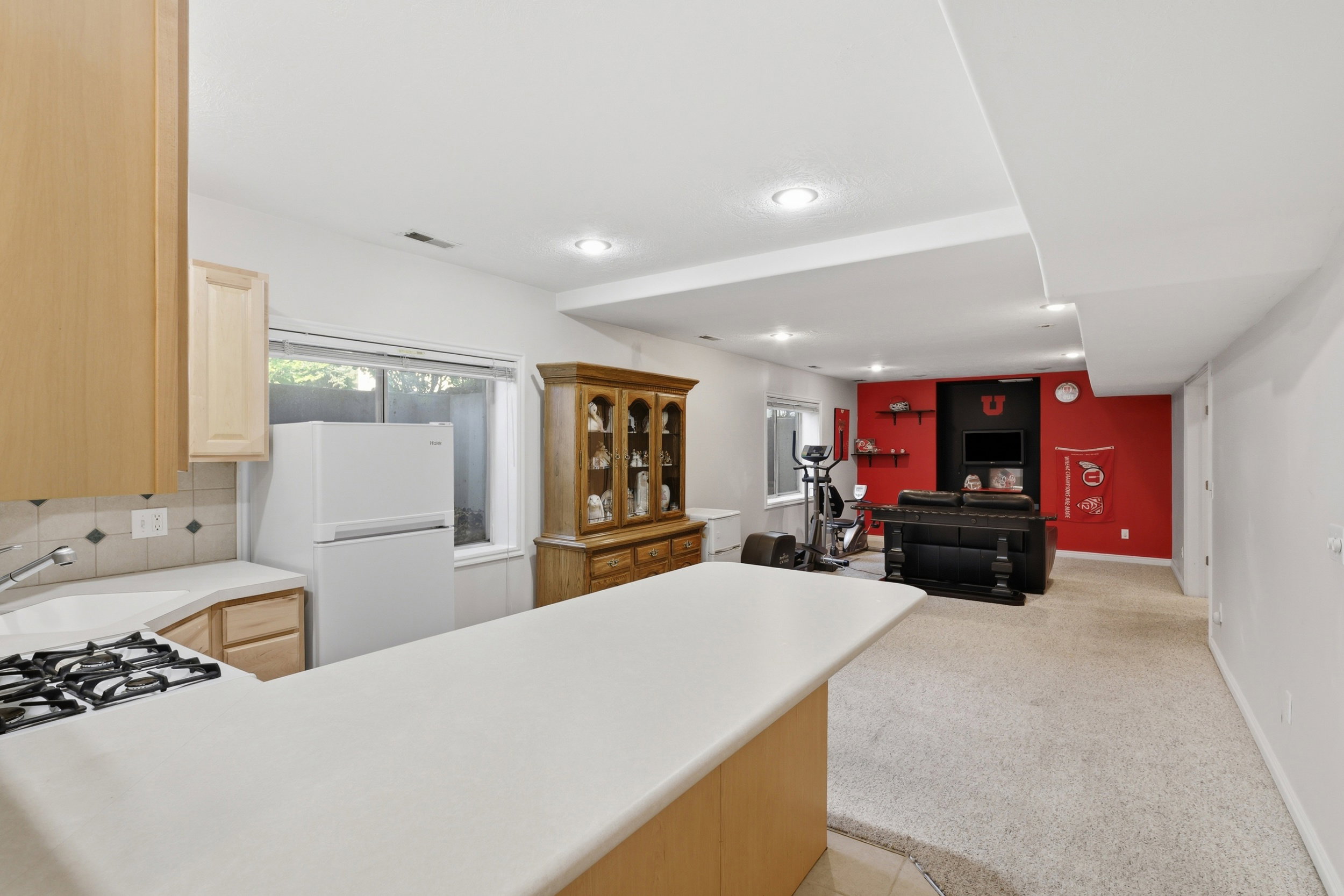 Open-concept lower level featuring a built-in countertop bar, light wood-finish cabinetry, and a full-size refrigerator