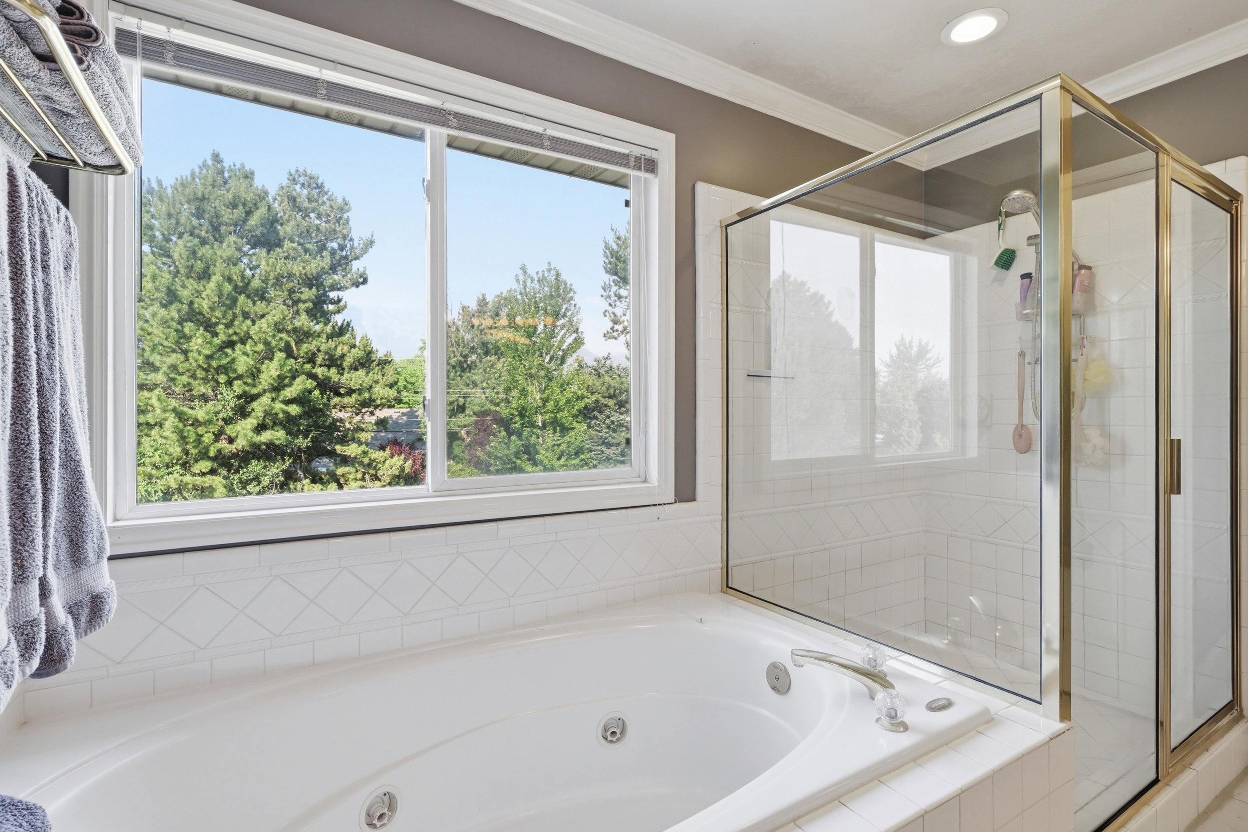 Soaking tub with integrated jets and chrome fixtures, surrounded by white ceramic tile