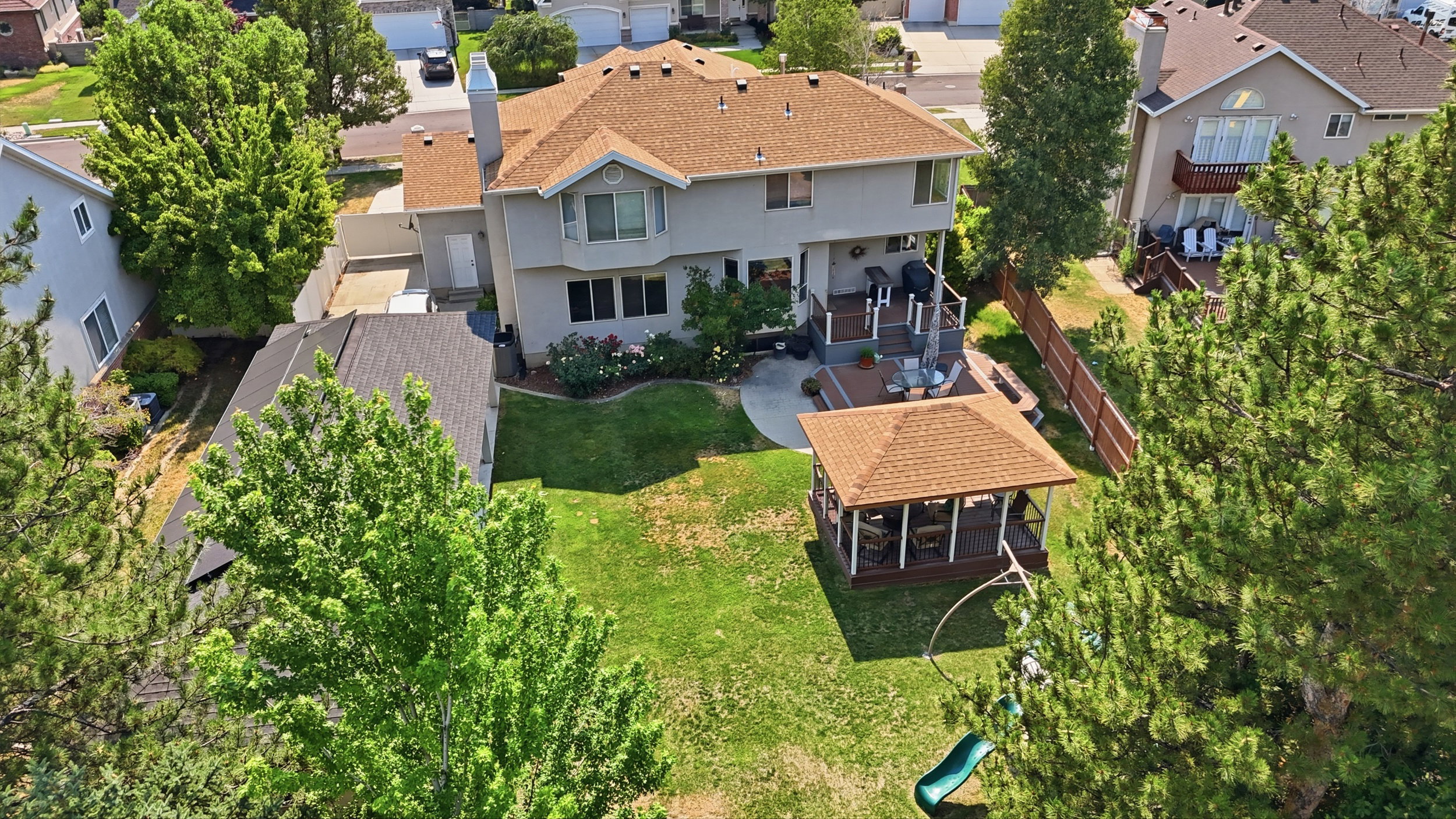Spacious backyard with a large lawn, covered gazebo, and multi-level deck