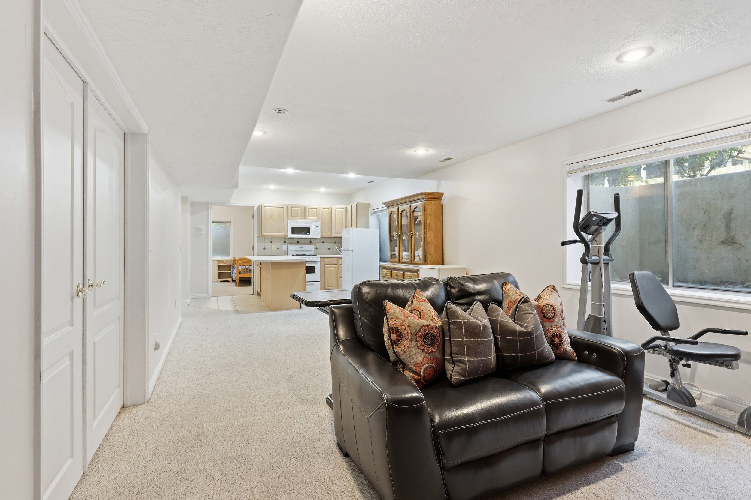 Open-concept lower level with recessed lighting and neutral carpeting