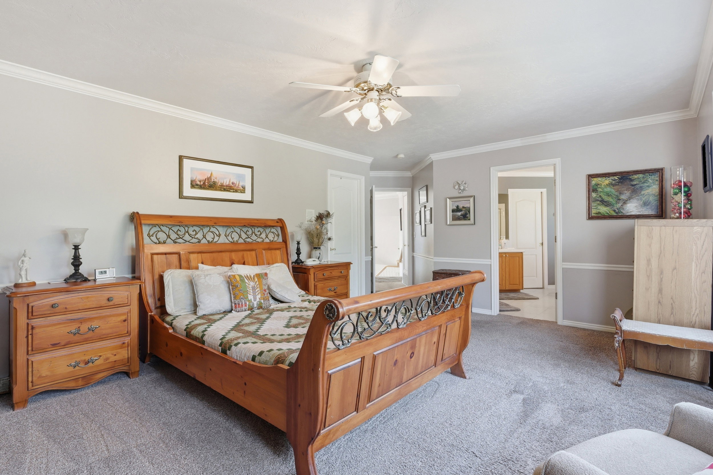 Carpeted bedroom featuring light gray walls with white crown molding and chair rail