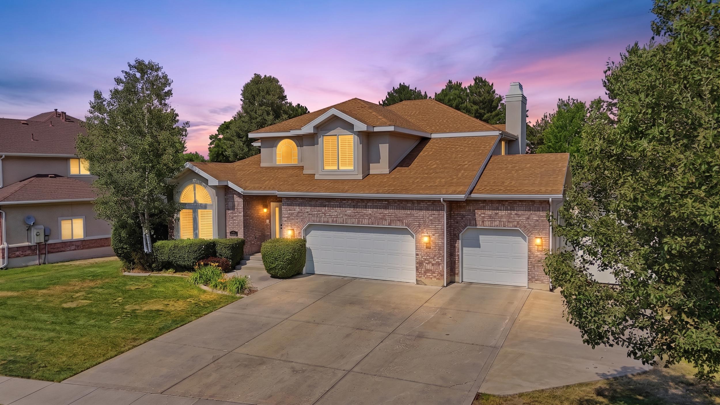 Stucco and brick exterior with a prominent arched window, a two-car garage, and an additional single-car garage