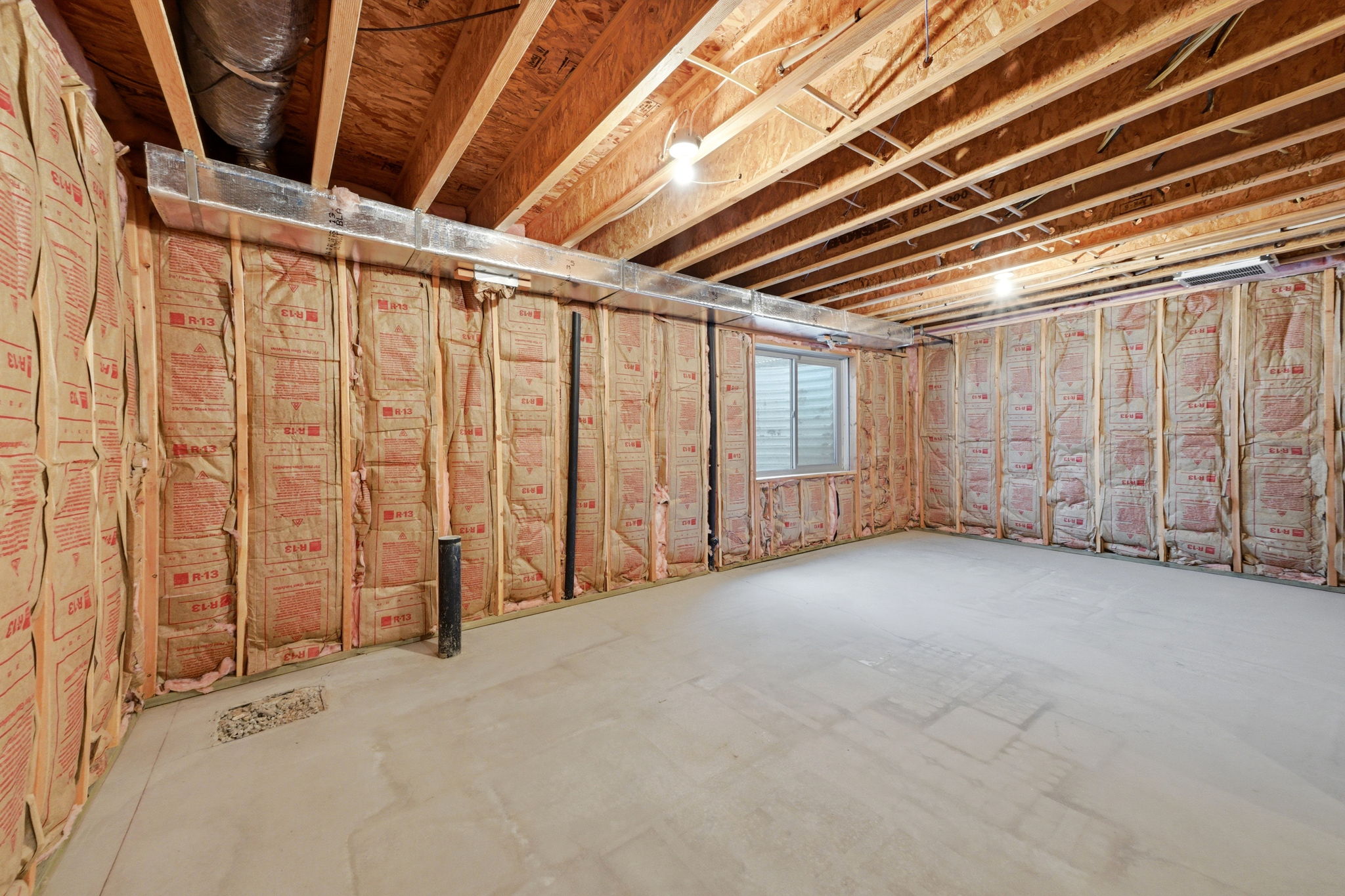 Unfinished basement area featuring exposed wood framing, ceiling joists, and concrete flooring