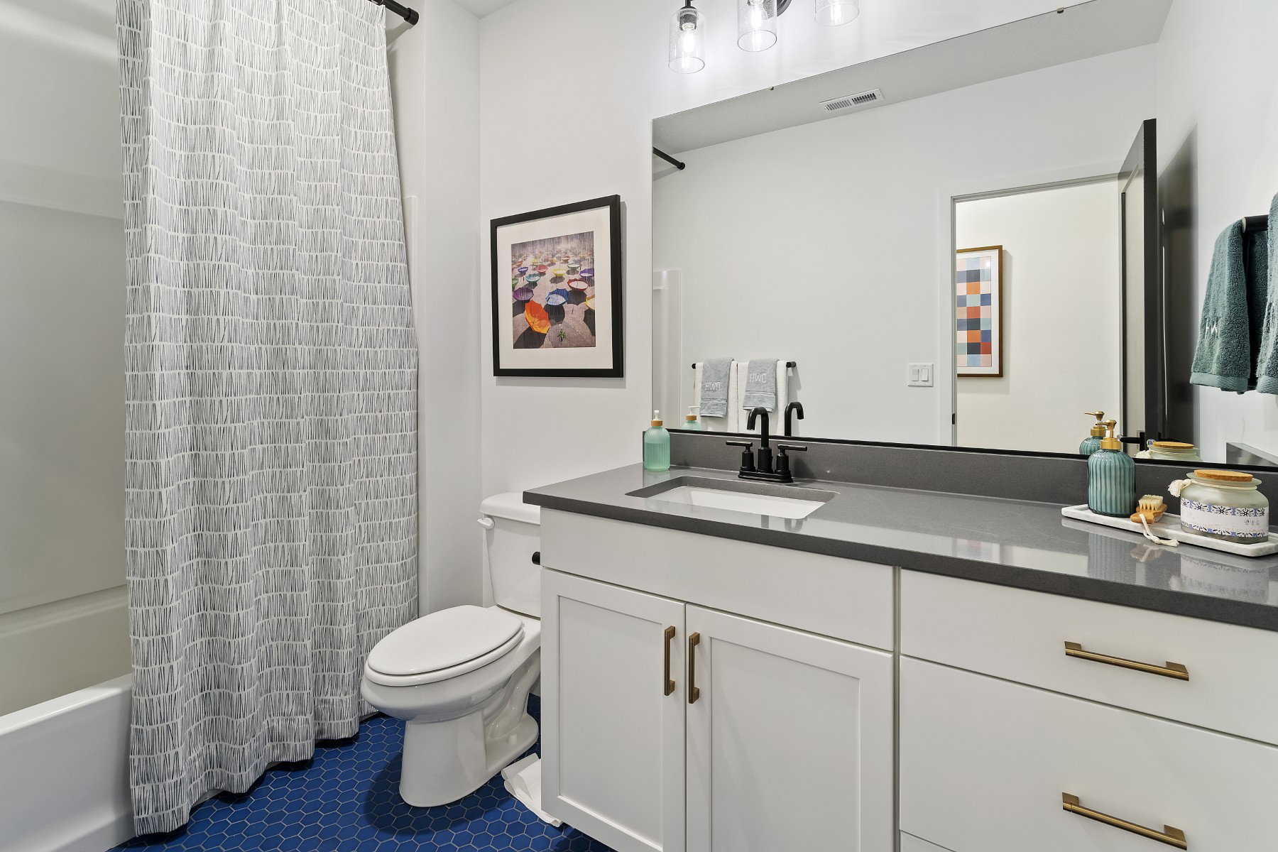 Bathroom featuring a white vanity with gold-tone hardware, dark countertop, and integrated sink