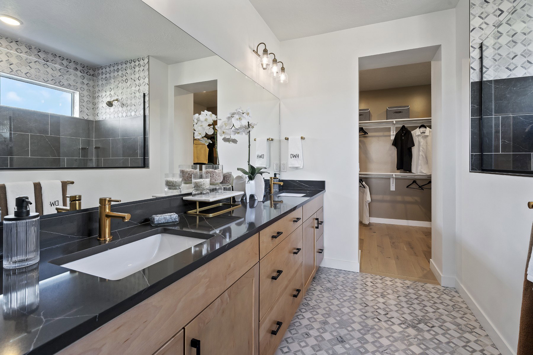 Dual vanity with undermount sinks, black countertops, and gold-finish fixtures