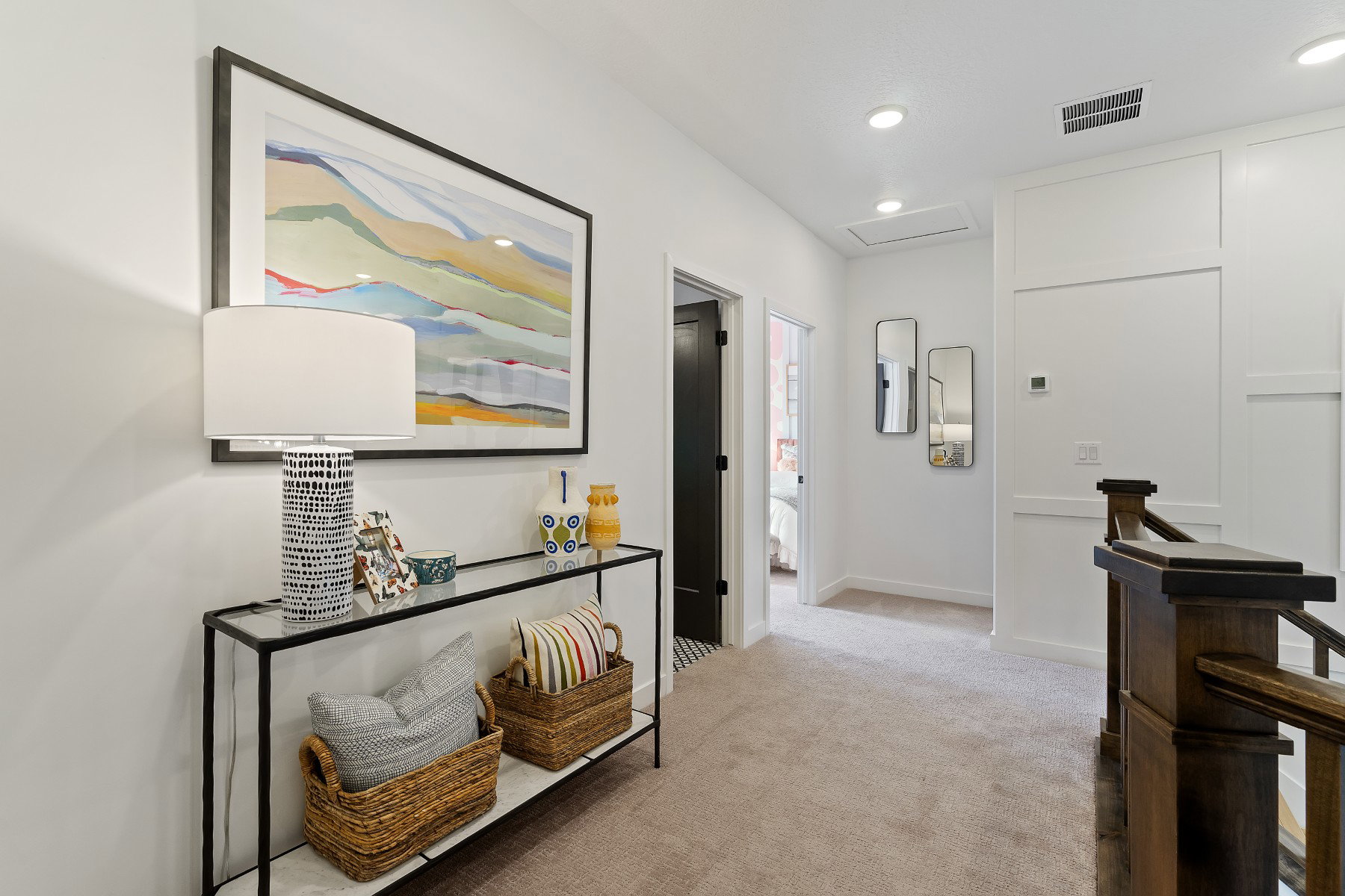 Upper-level hallway with neutral carpet flooring, recessed lighting, white walls, and a dark wood staircase banister