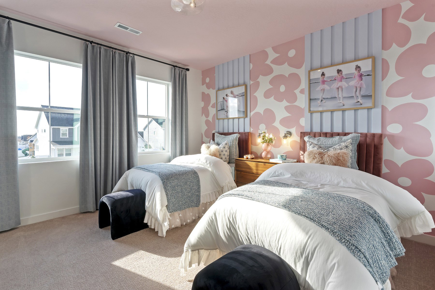 Bright room featuring two large windows with gray drapery, textured accent wall with floral pattern, pink ceiling, and carpeted flooring
