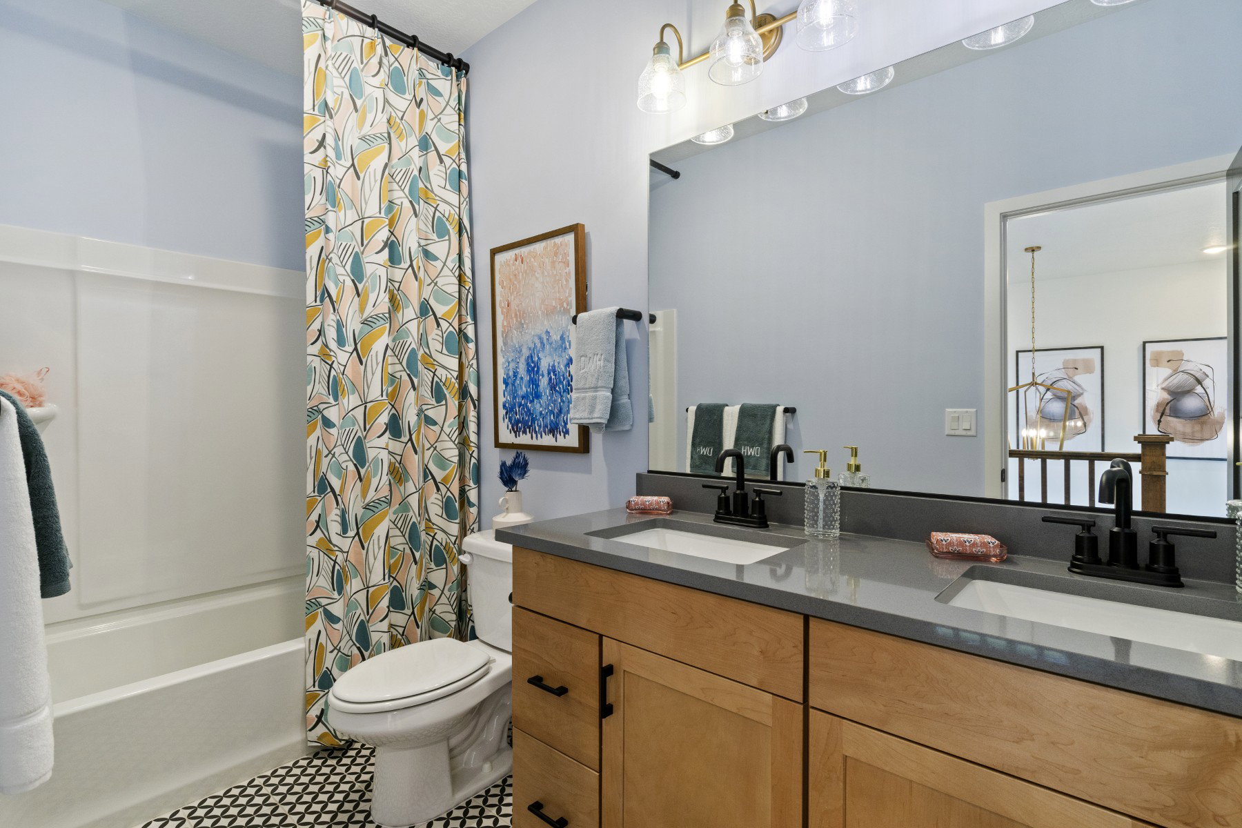 Bathroom featuring a double vanity with wood-finish cabinetry, a grey countertop, and matte black fixtures