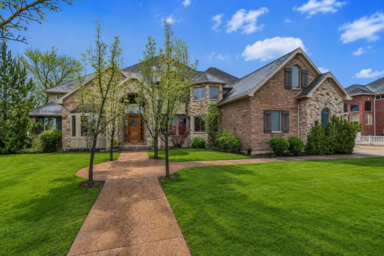 Stately two-story residence featuring a brick and stone facade with decorative shutters
