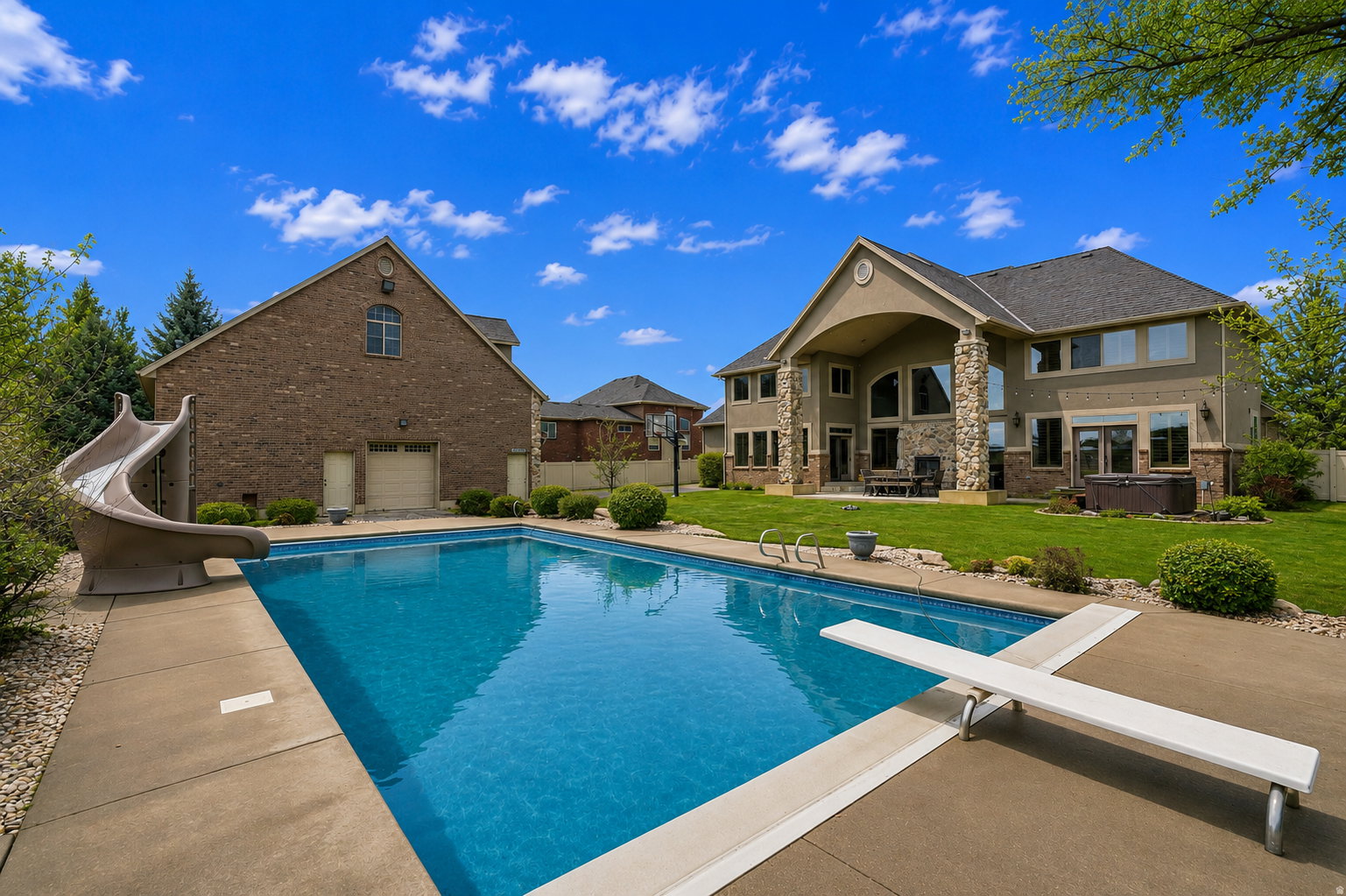 Expansive inground swimming pool featuring a diving board and attached slide