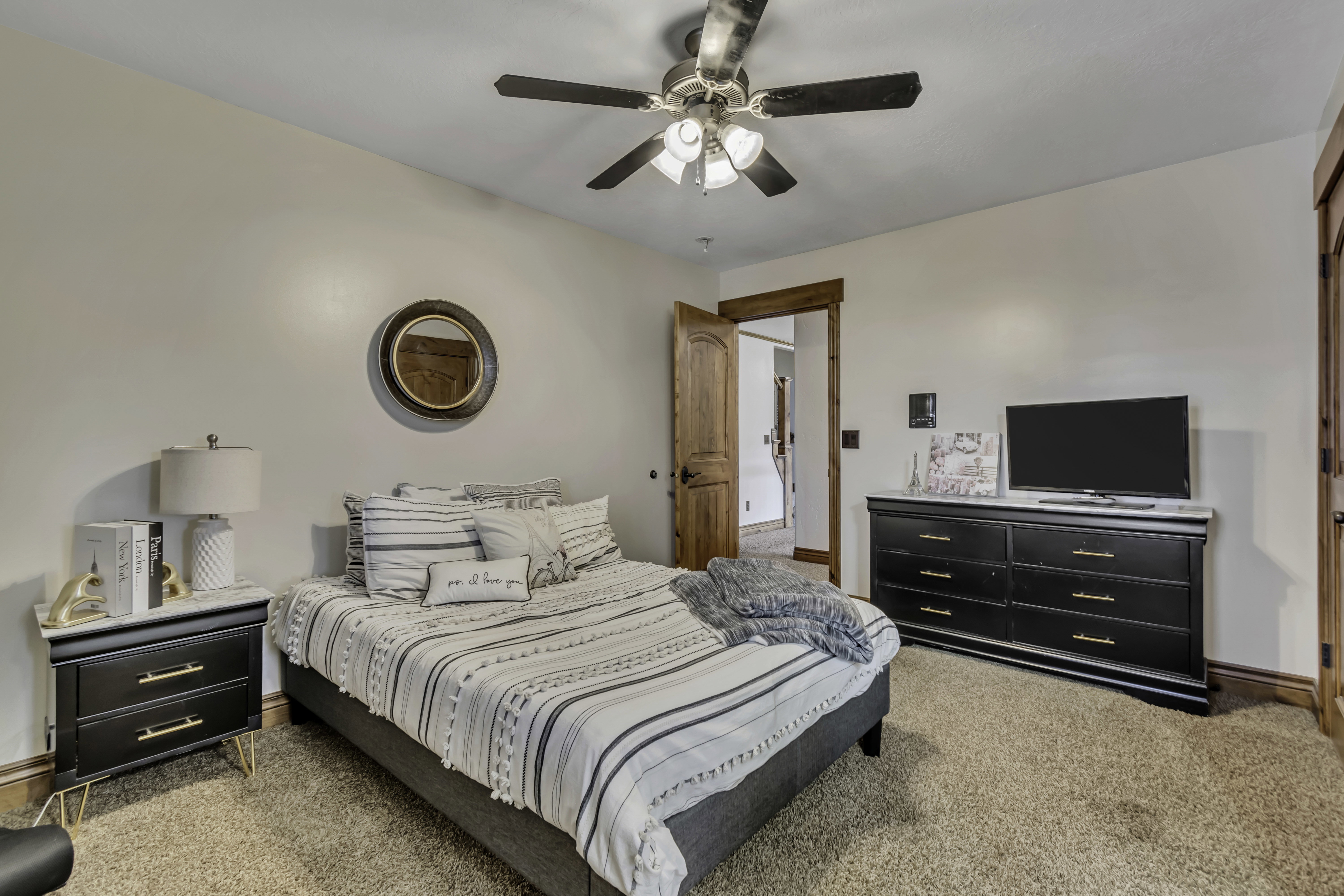 Carpeted room featuring a ceiling fan, wood trim, and a wood-paneled door