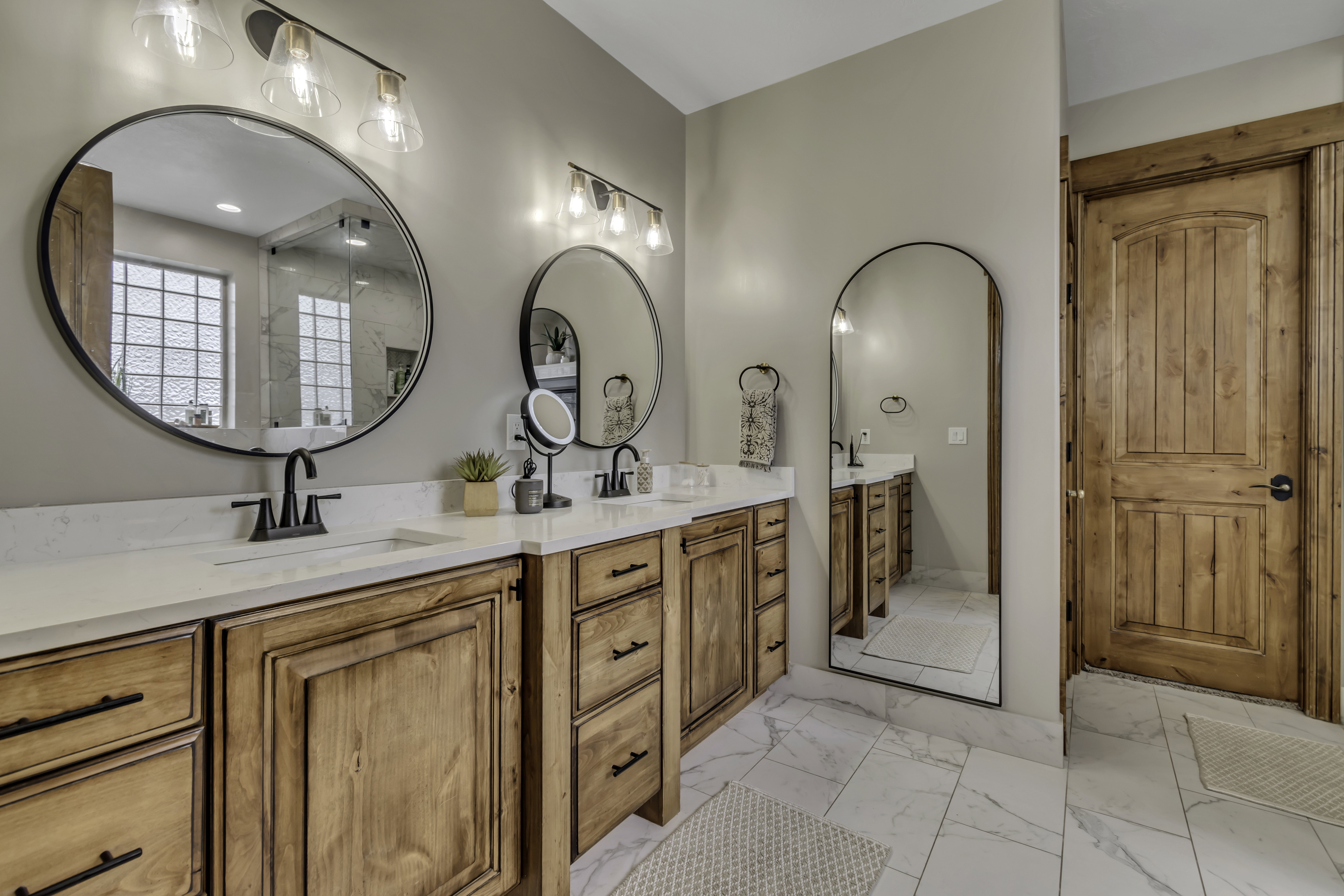 Dual sink vanity featuring wood cabinetry, white countertops, and matte black fixtures