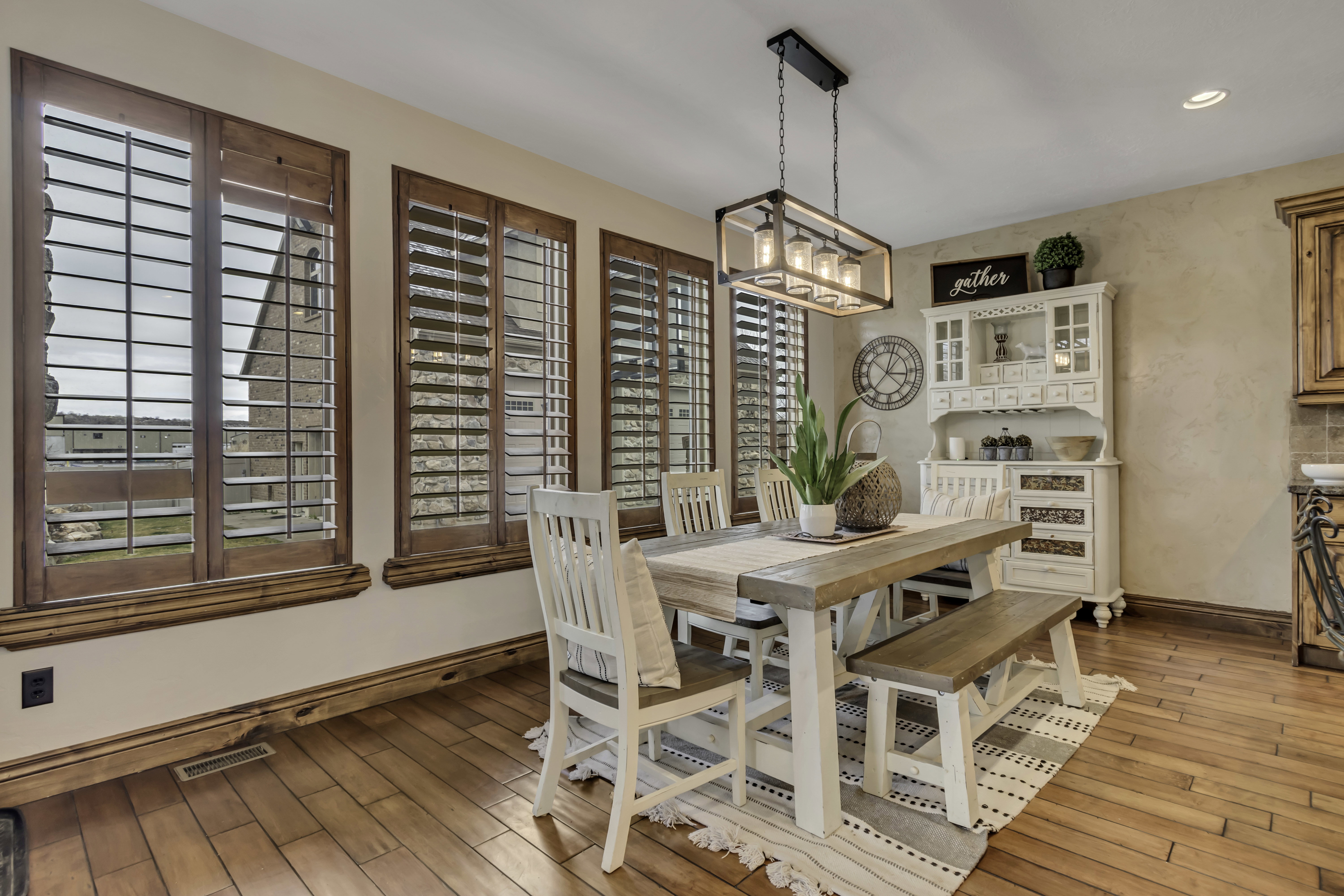 Dining area featuring wood-finish flooring and three windows with wooden plantation shutters