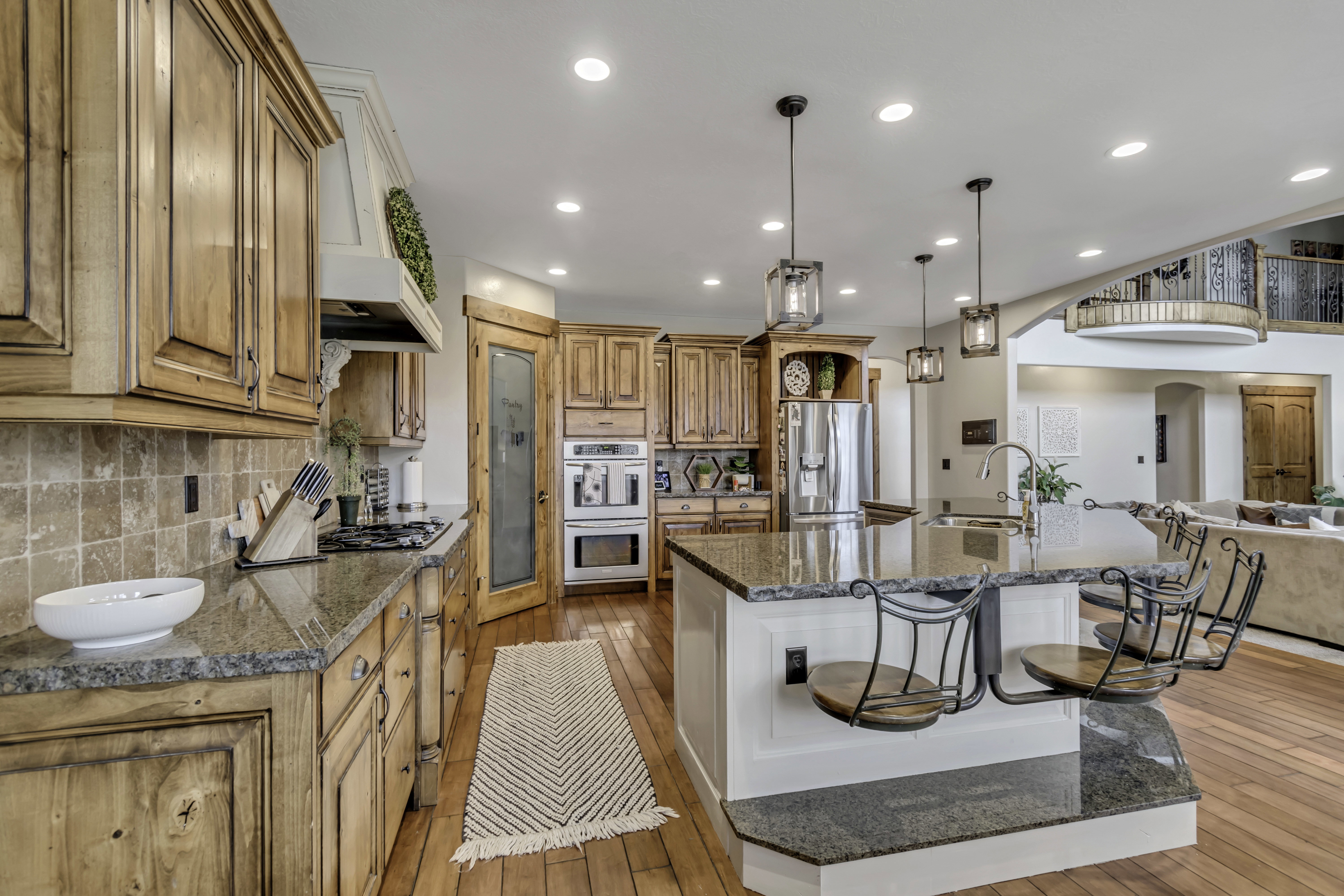 Gourmet kitchen featuring wood-finish cabinetry, granite countertops, stainless steel appliances, and a central island with bar seating