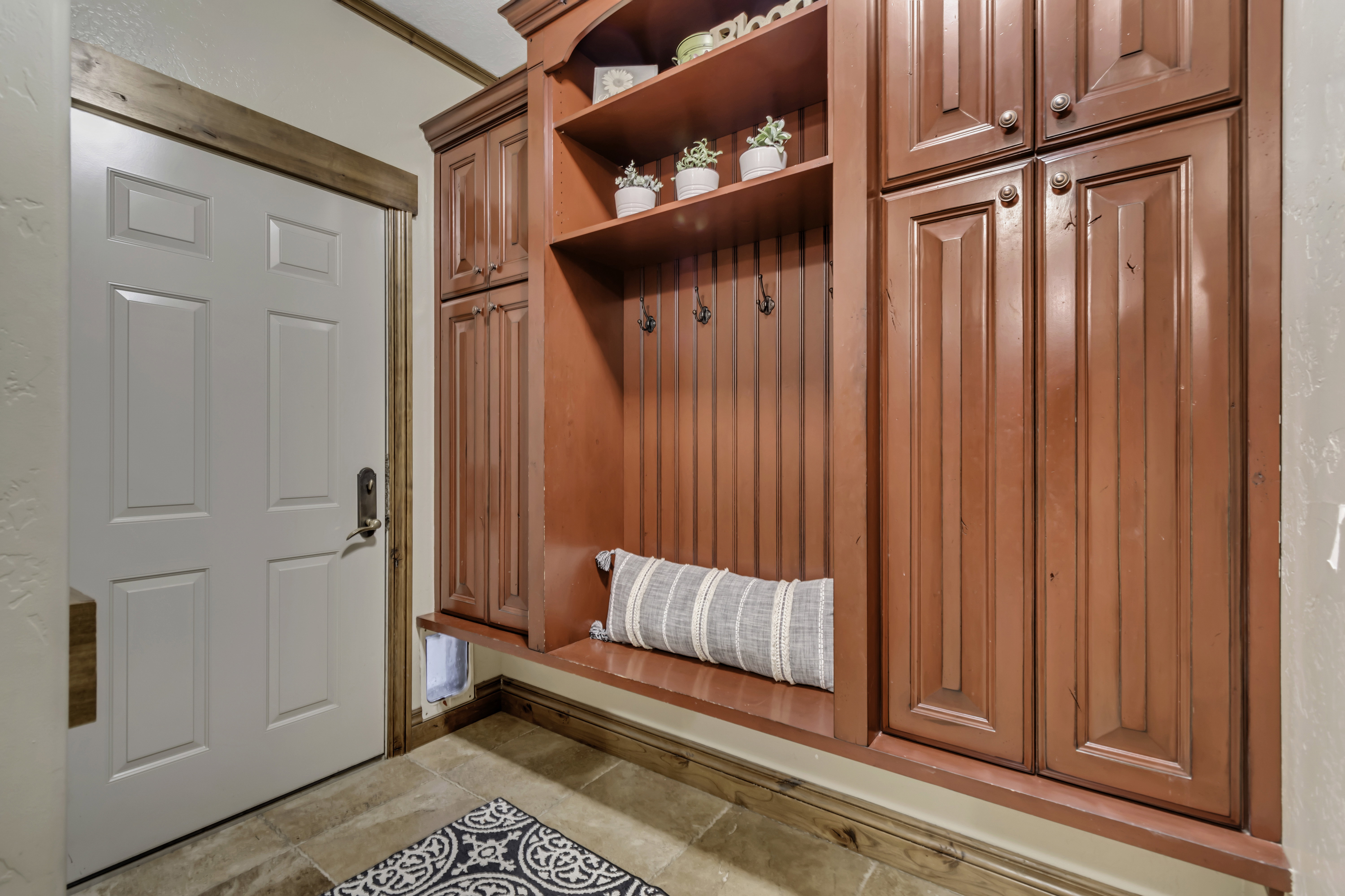 Custom built-in entryway storage with rich red cabinetry and shelving