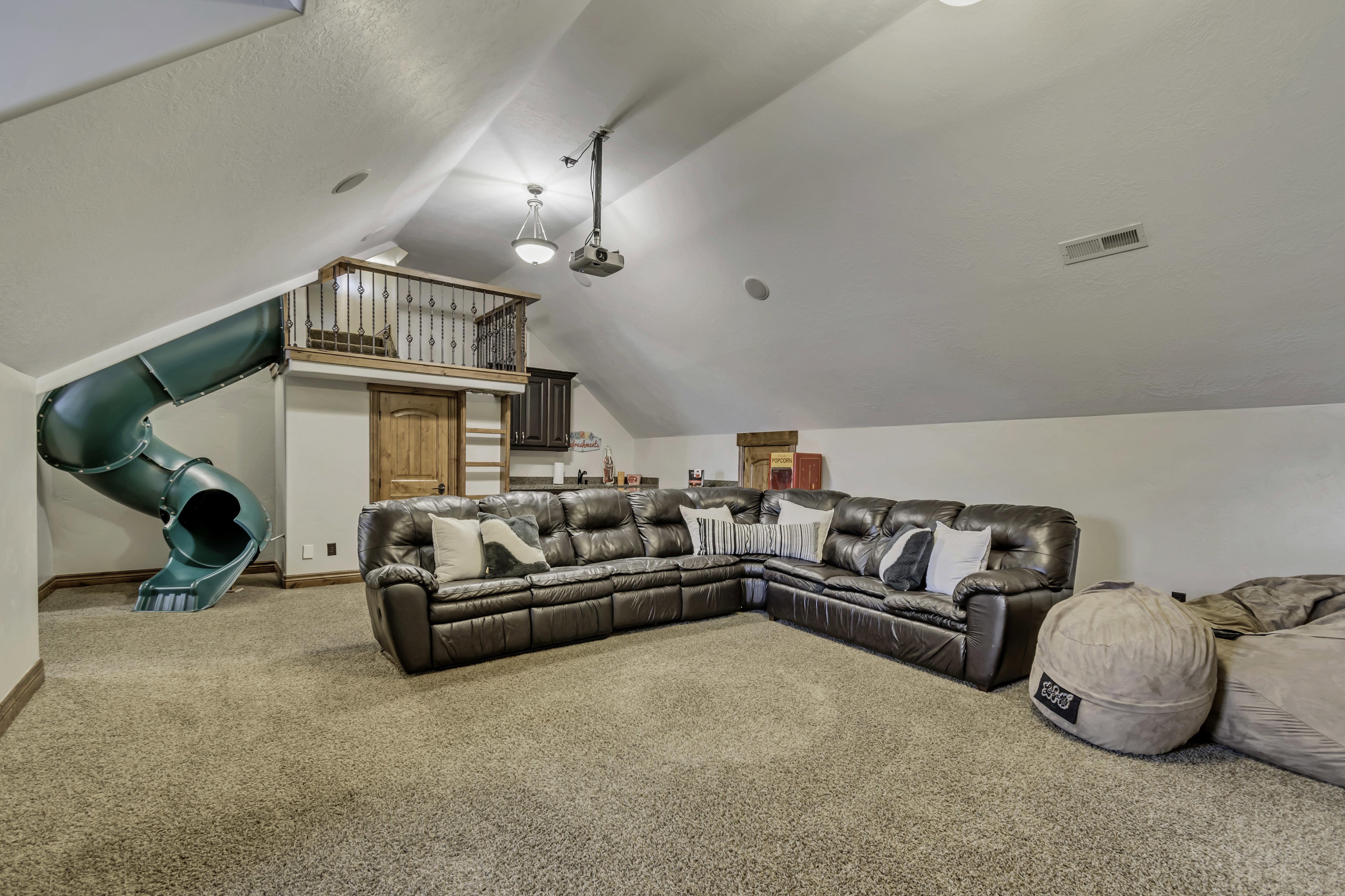 Spacious recreation room featuring a built-in slide, carpeted flooring, and a recessed media projector