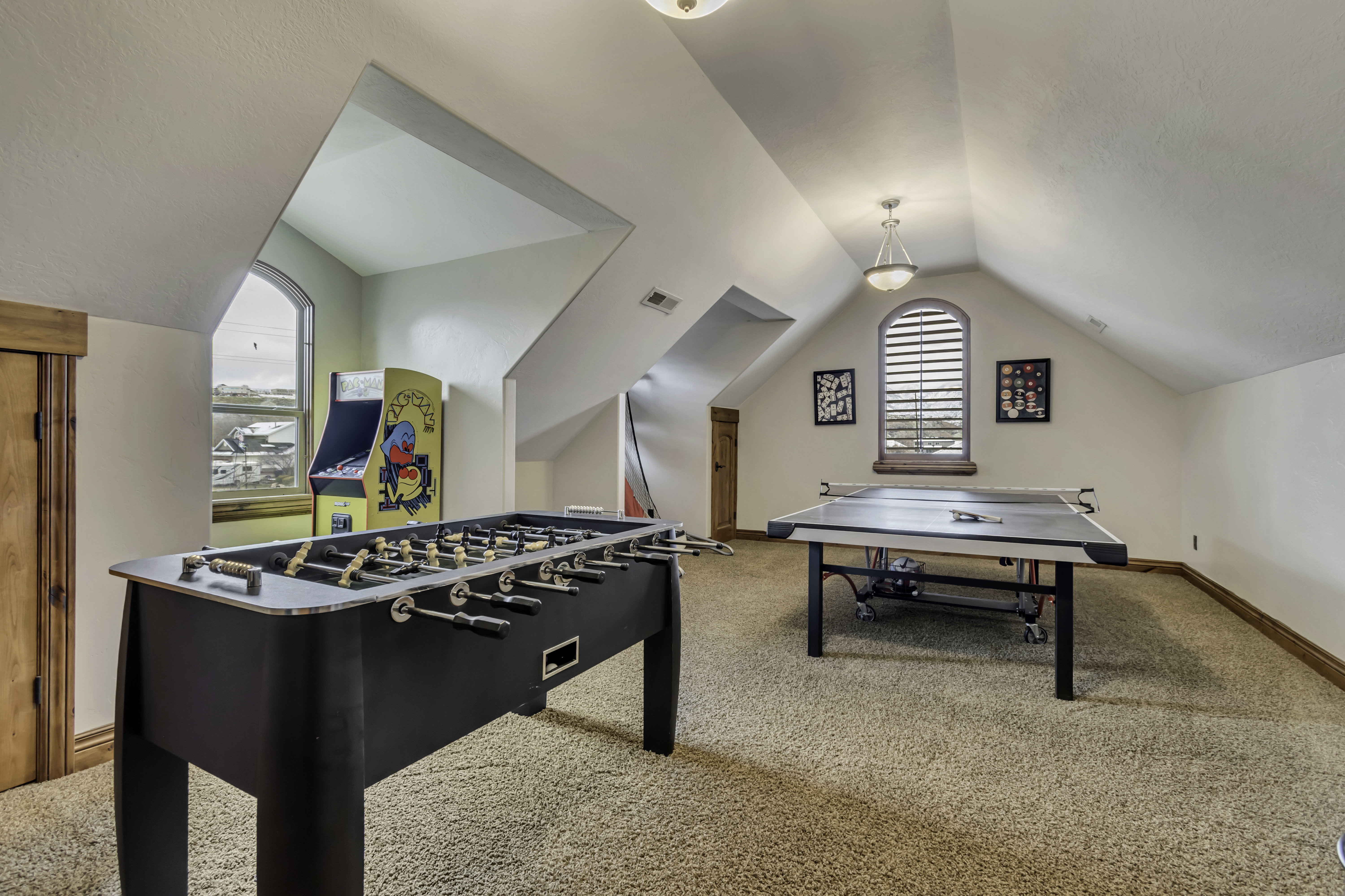 Carpeted loft space featuring vaulted ceilings, a prominent arched window, and warm wood trim