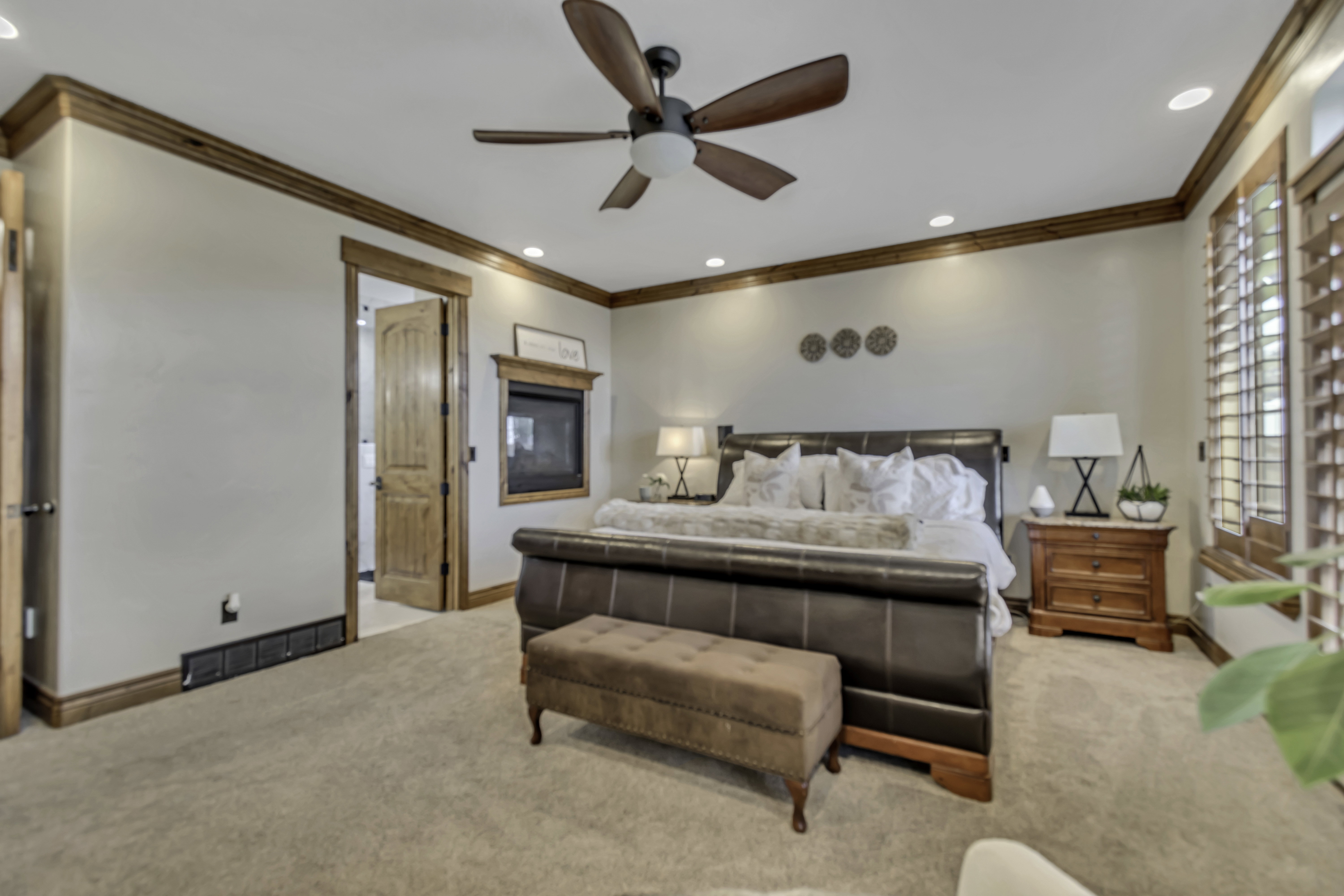 Spacious room featuring neutral wall tones, rich wood-tone trim, crown molding, and a ceiling fan