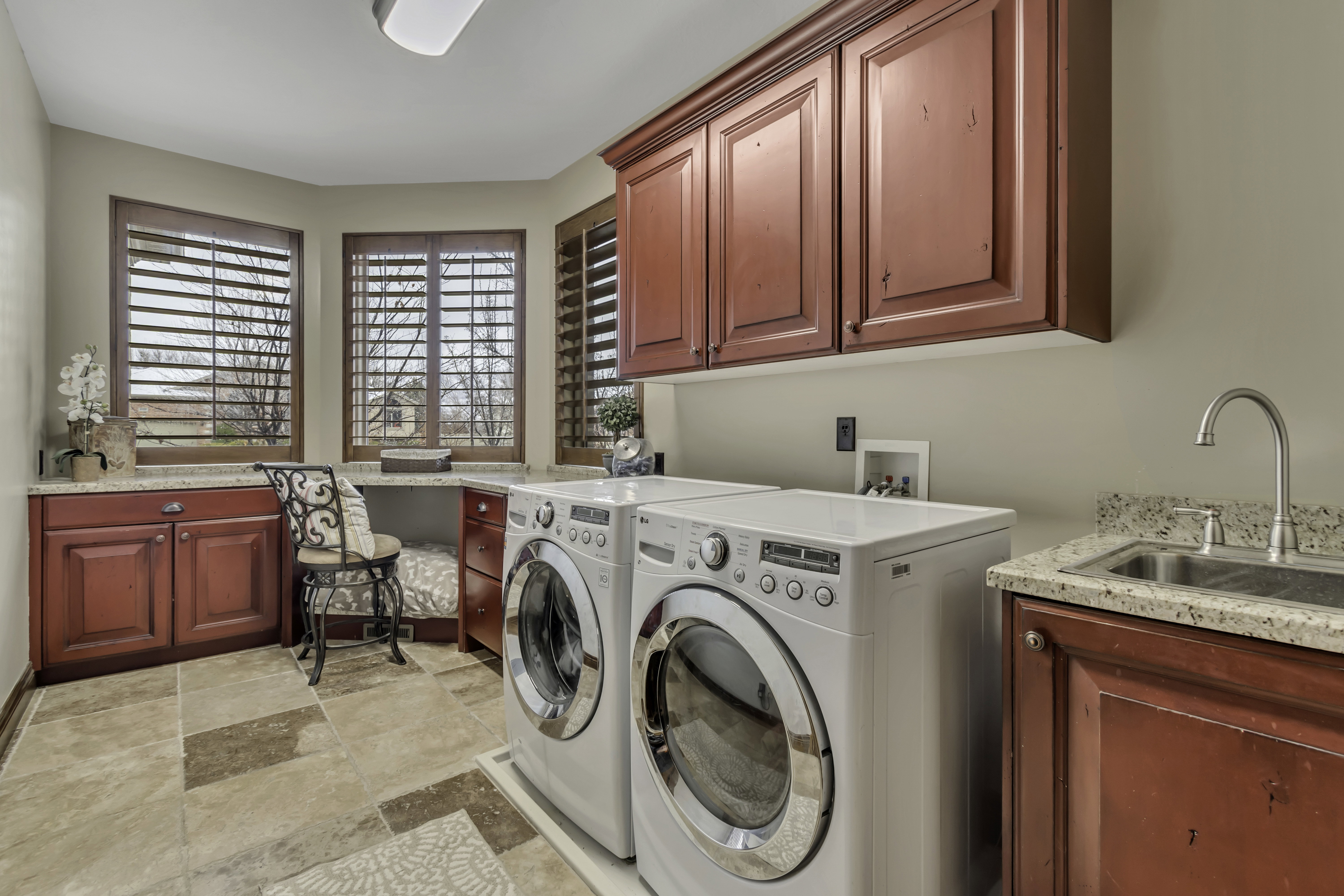 Utility room featuring wood-finish cabinetry, light-toned countertops, and tile flooring