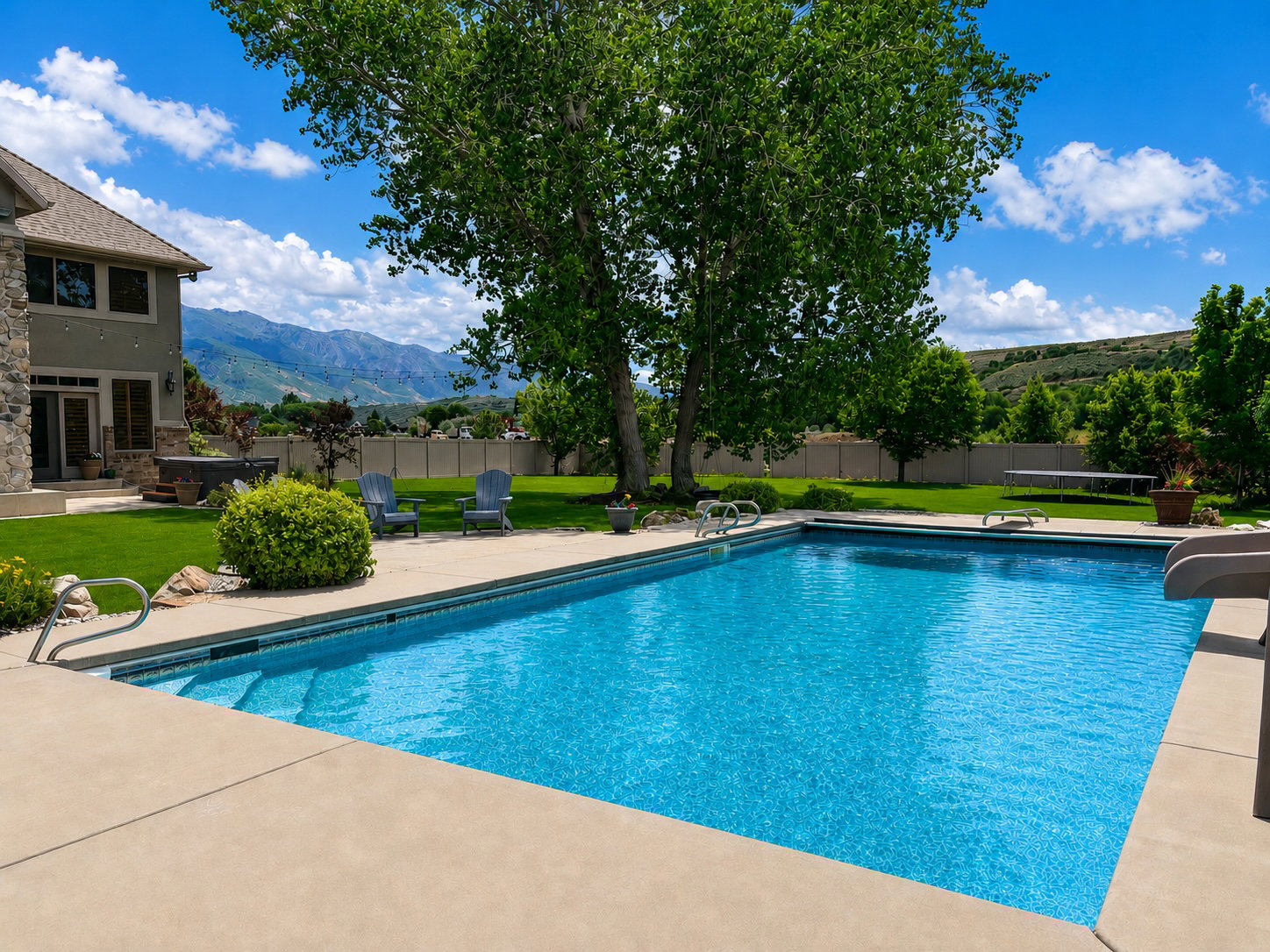 Expansive backyard featuring a large in-ground swimming pool, concrete patio, and manicured lawn