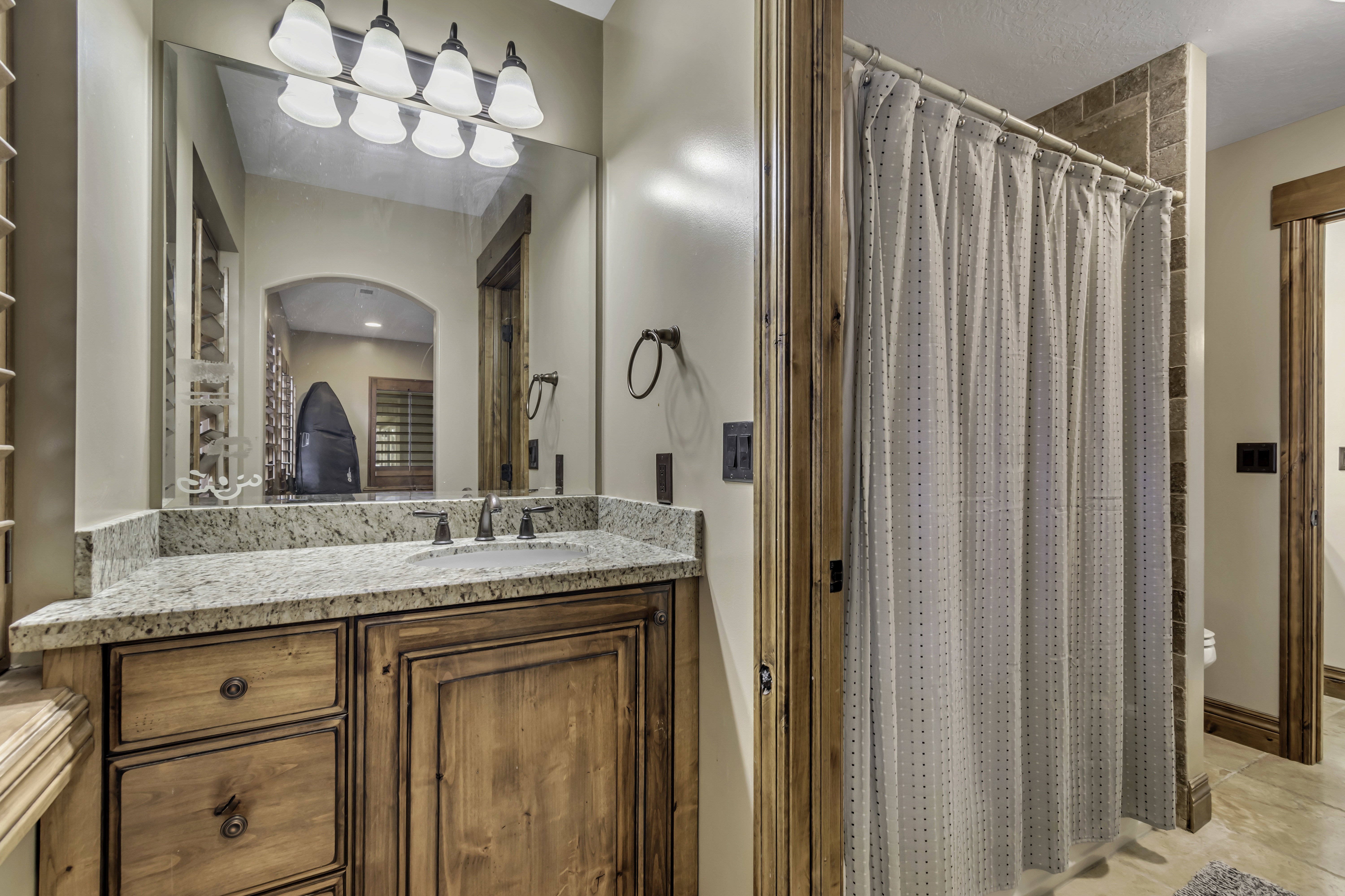 Bathroom featuring a wood-finish vanity with a granite countertop and an undermount sink