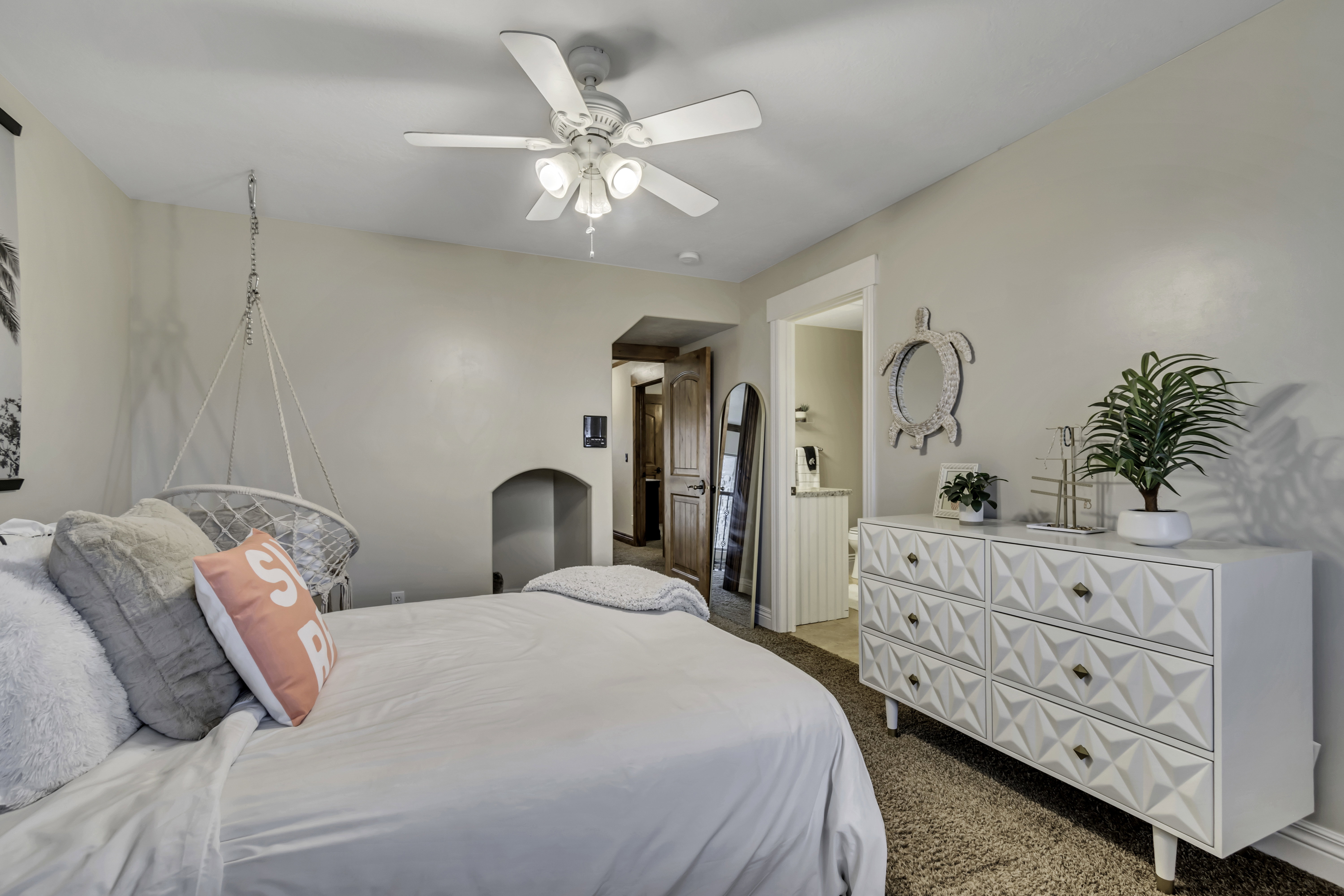 Carpeted room featuring a ceiling fan with integrated lighting, a recessed wall niche, and an entryway with a wood-finish door