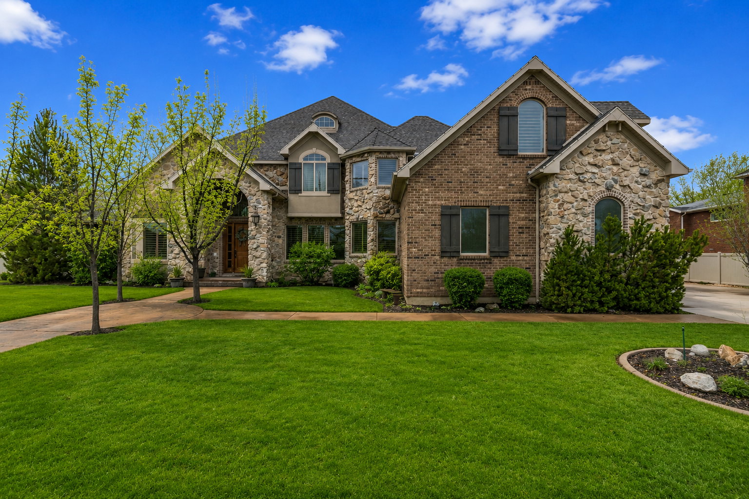 Stone and brick exterior with arched windows, dark shutters, and a covered entry