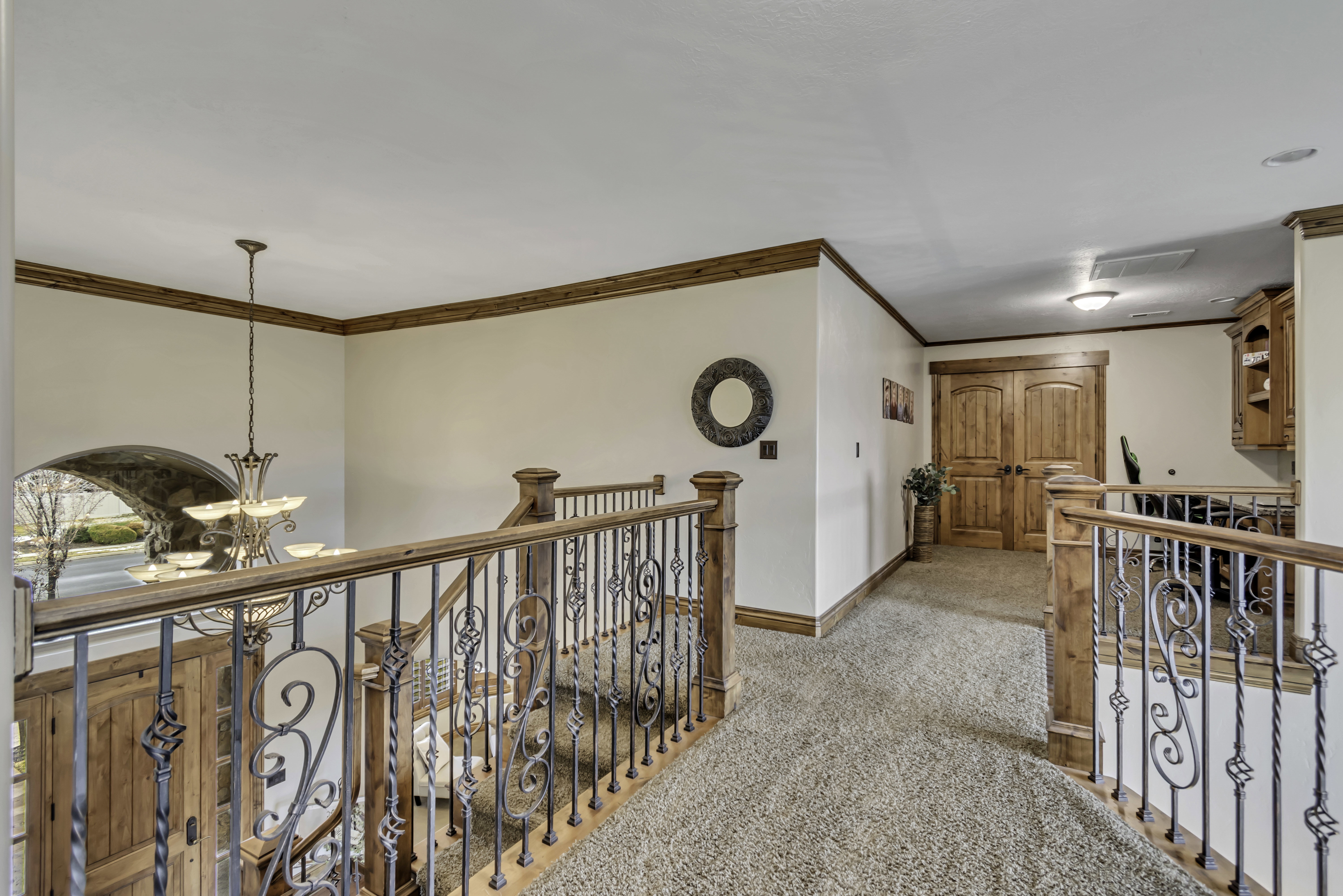 Upper-level landing with plush carpeting, wood-finish trim, and wrought iron railings