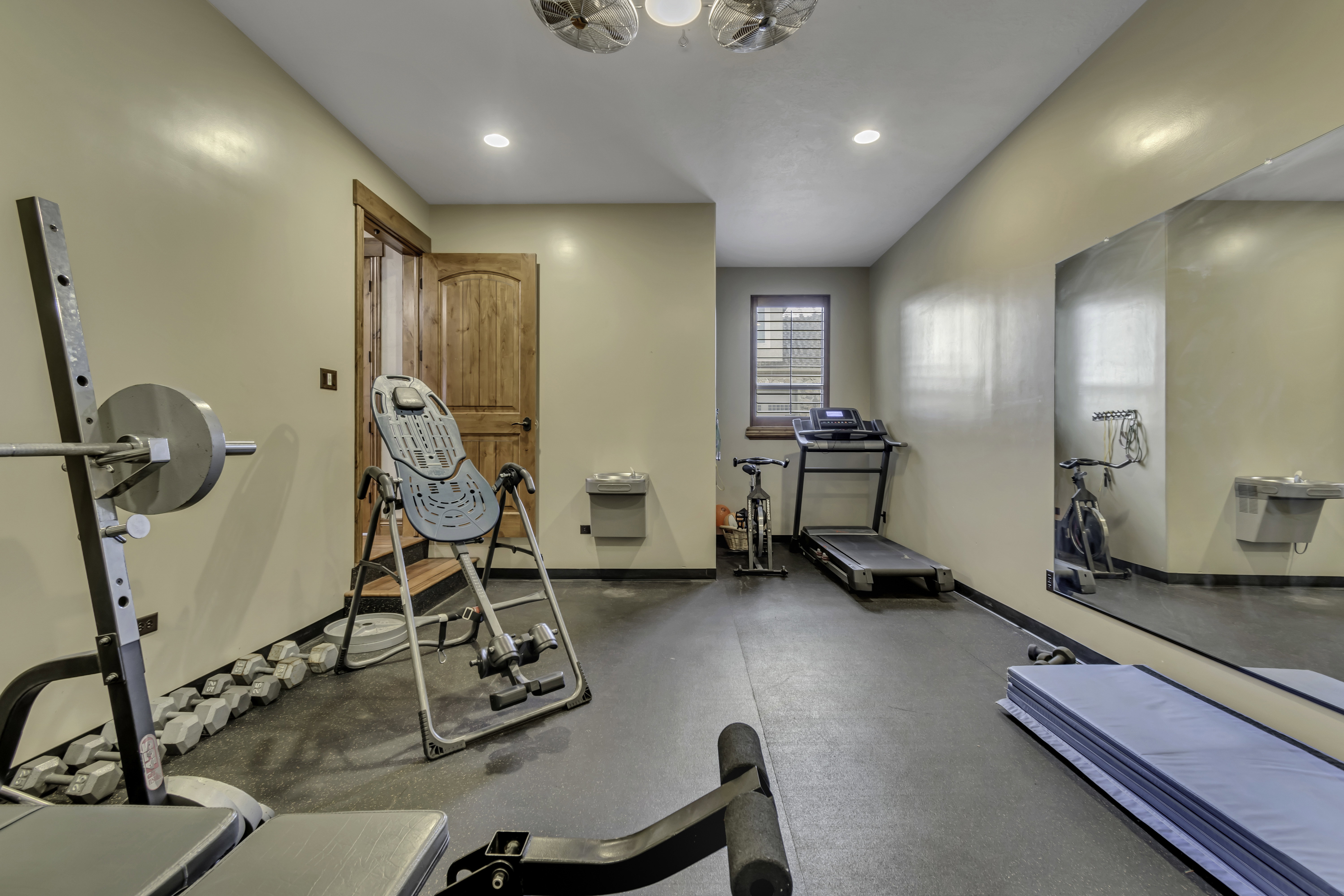 Spacious room featuring neutral wall tones, recessed lighting, and a durable rubber-finish floor